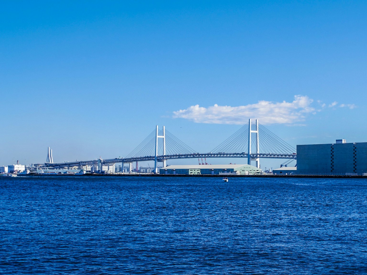 View of Yokohama Bay Bridge under a blue sky and water