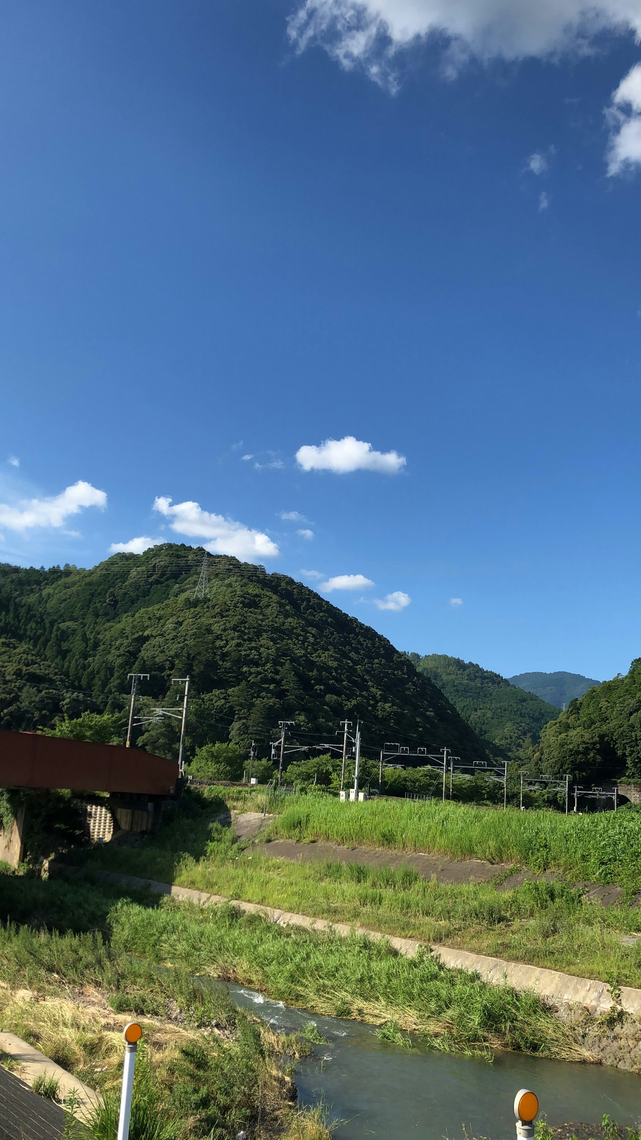 亀岡の川沿いに広がる緑の山並みと青空