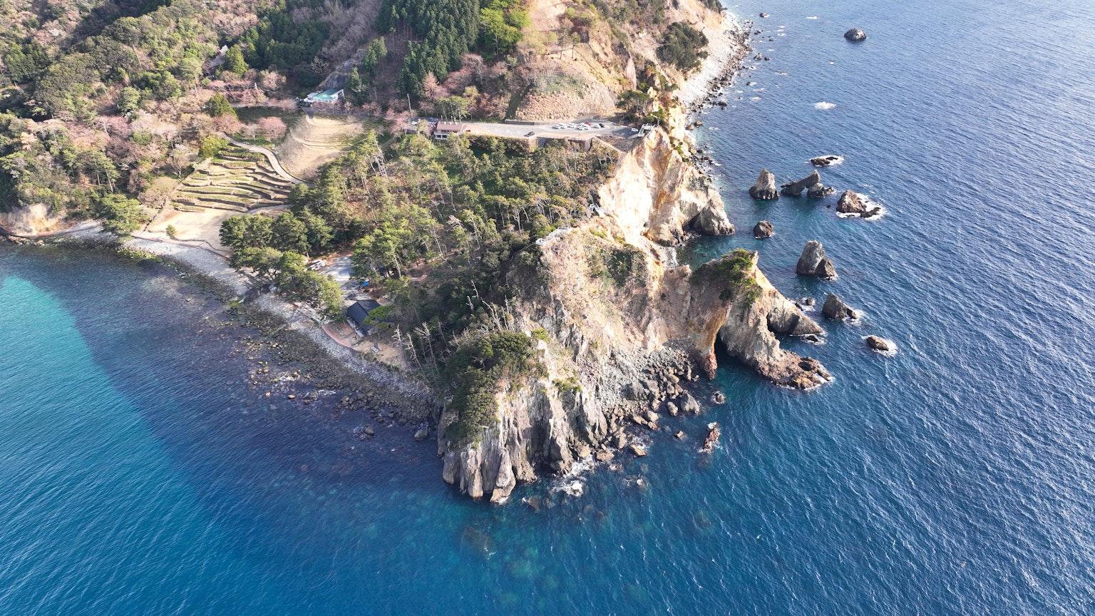 Aerial view of a rocky coastline with clear blue water