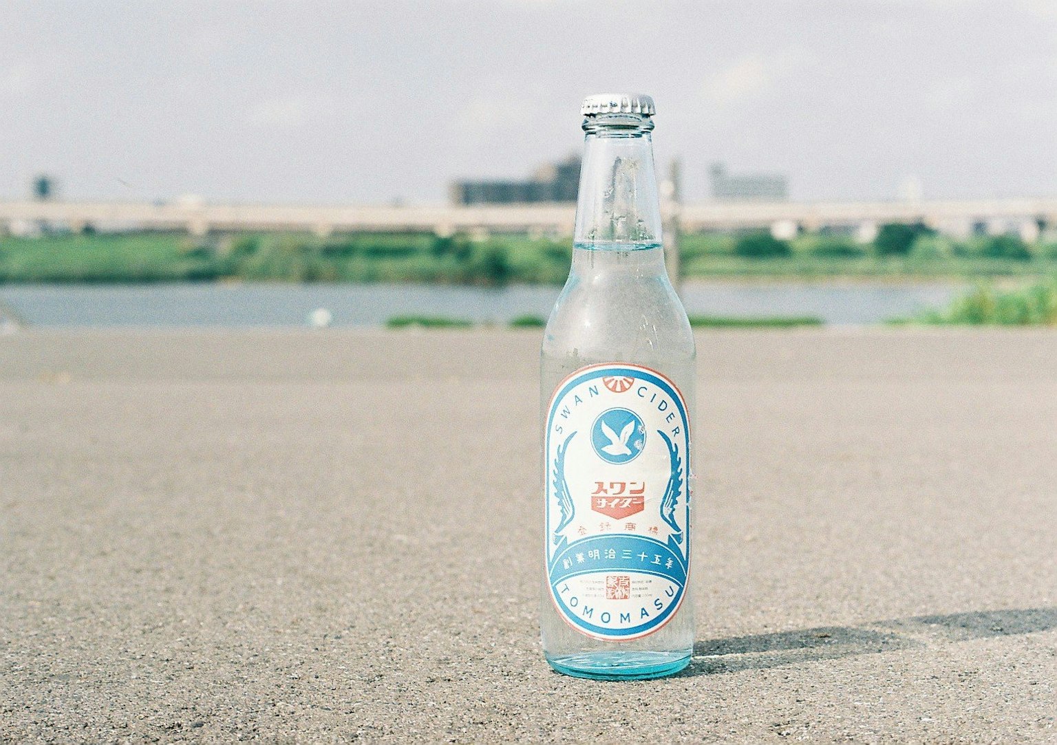 一瓶藍色標籤的飲料放置在河邊