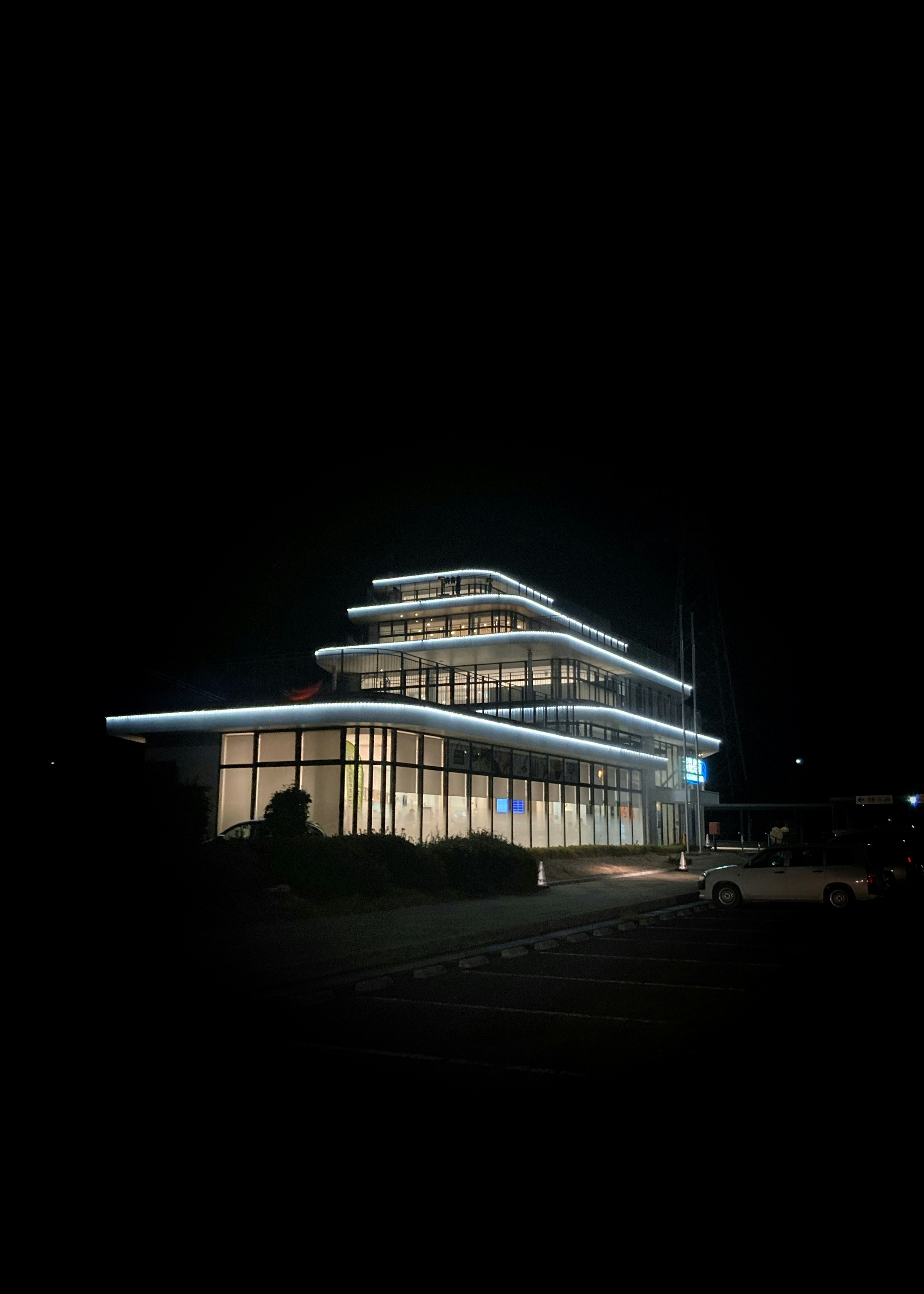 夜に照らされた現代的な建物の外観 複数の層を持つデザイン 明るい窓と青い照明
