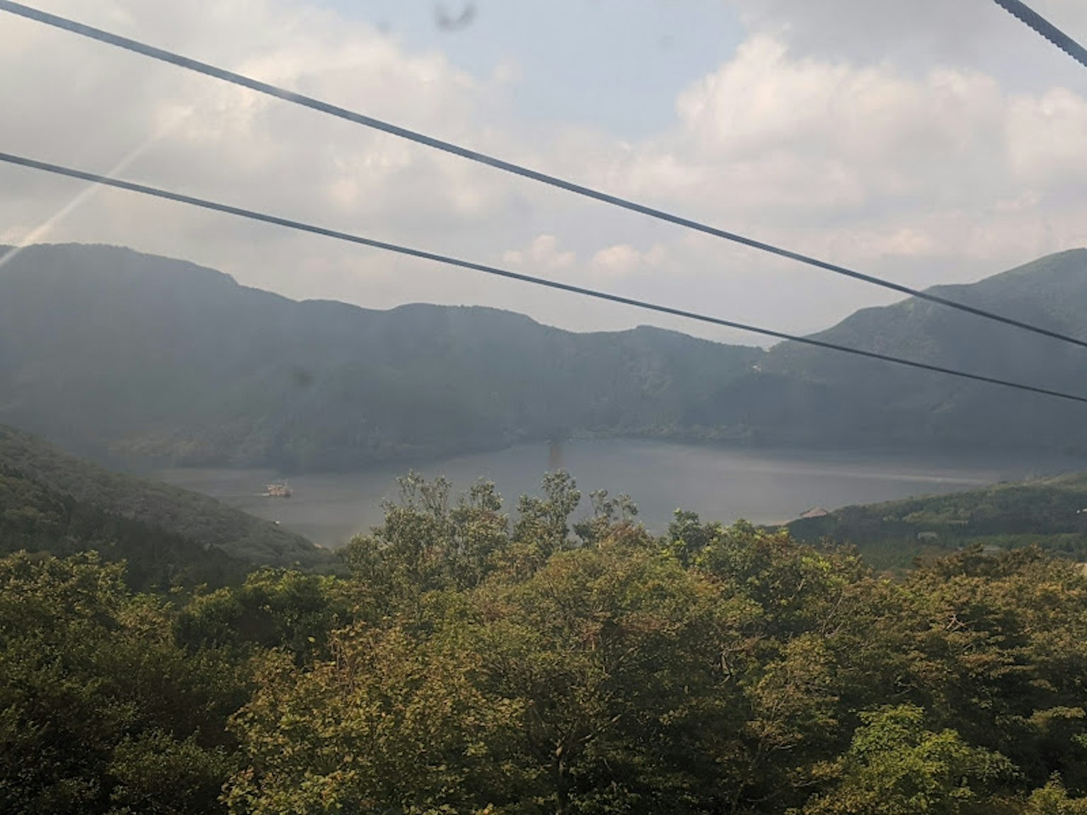 Pemandangan pegunungan dan danau dengan kabel listrik di latar depan