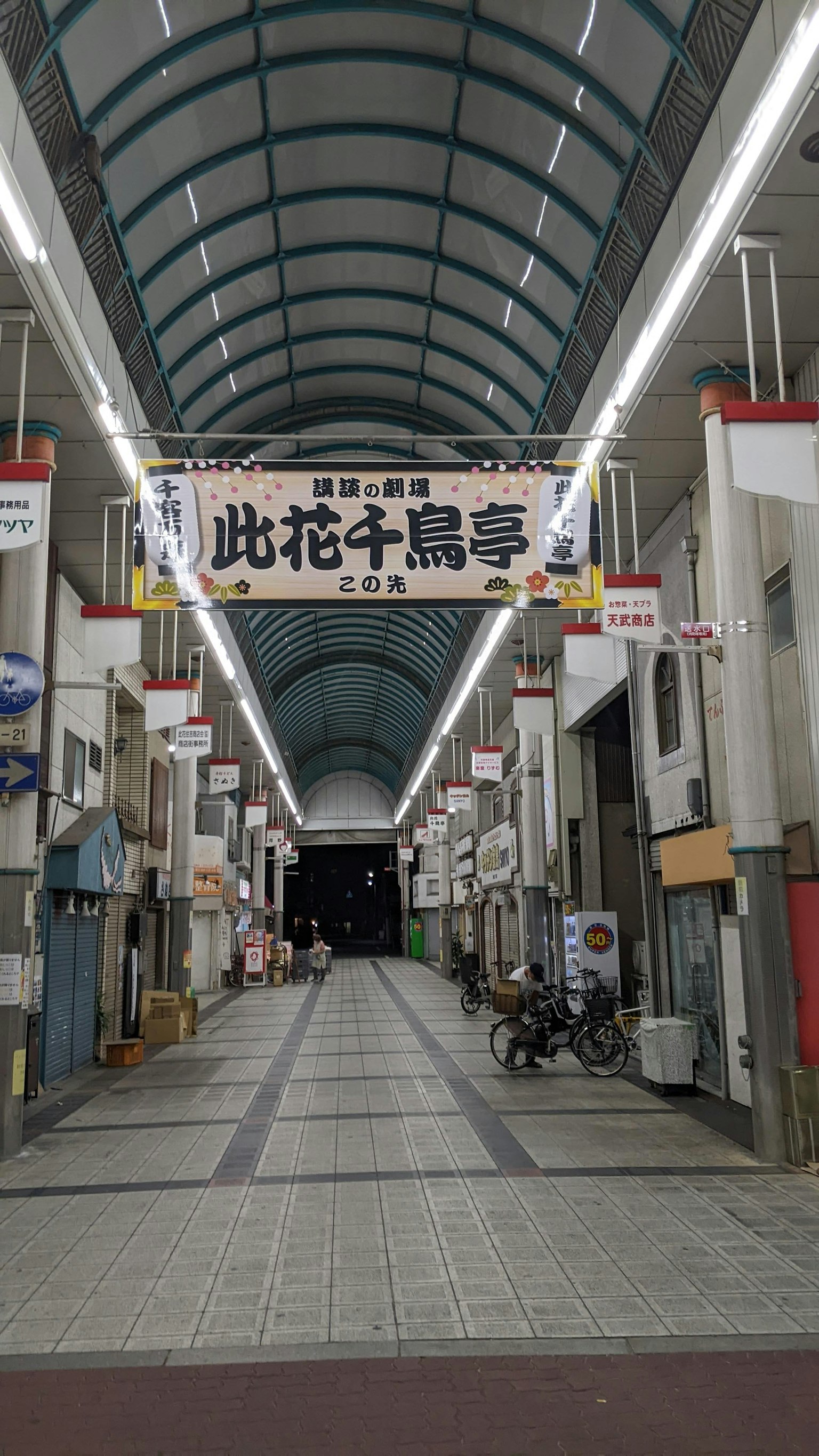 Vista di una strada di un'arcade commerciale con un lungo passaggio illuminato e ingressi dei negozi