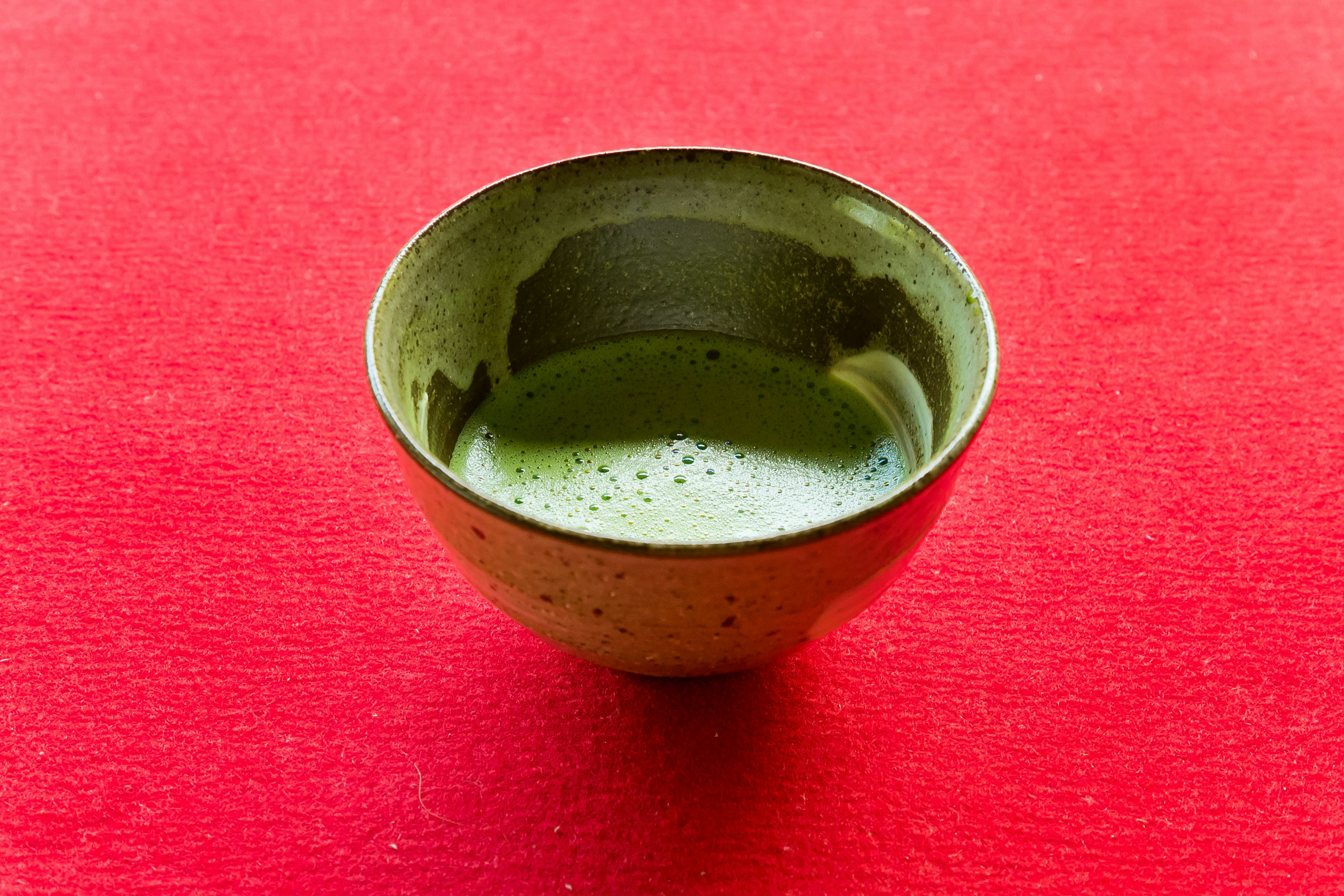 赤い布の上に置かれた抹茶の小さな茶碗