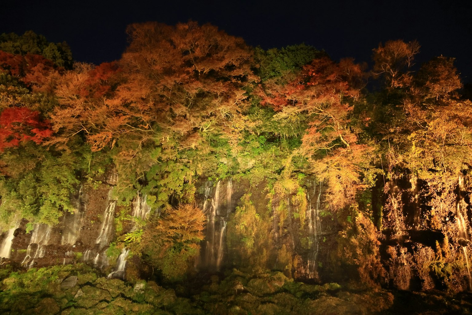 Hermoso paisaje de una cascada y follaje otoñal de noche