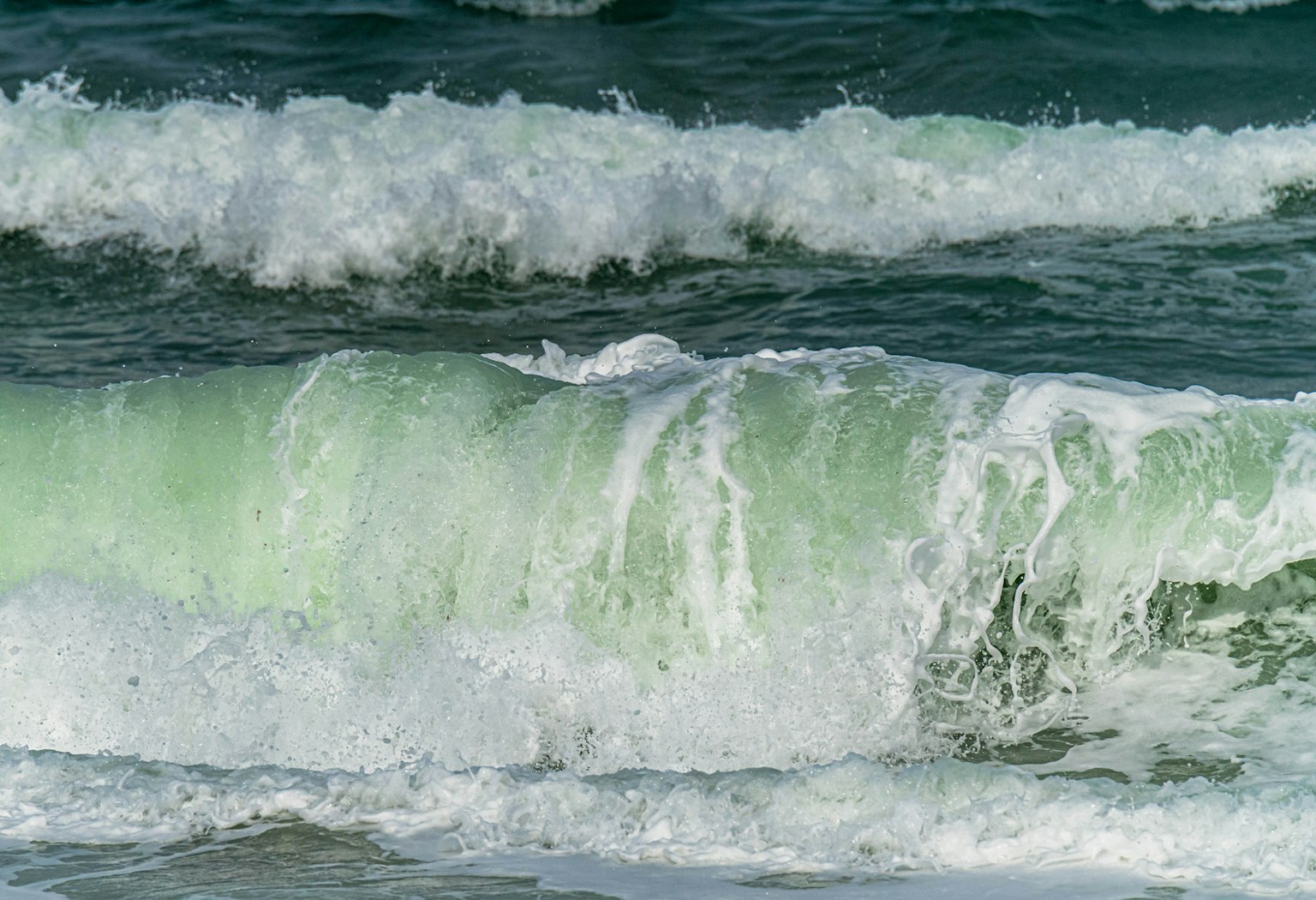 Primo piano di onde oceaniche con tonalità verdi e schiuma bianca