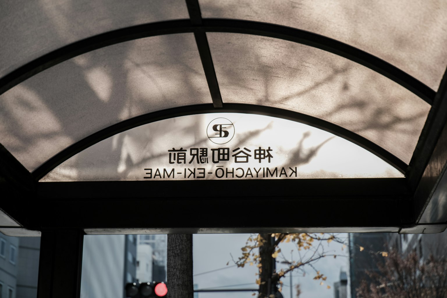 這張圖片展示了神奈川縣橫濱的車站標誌，陽光在結構下投射出陰影
