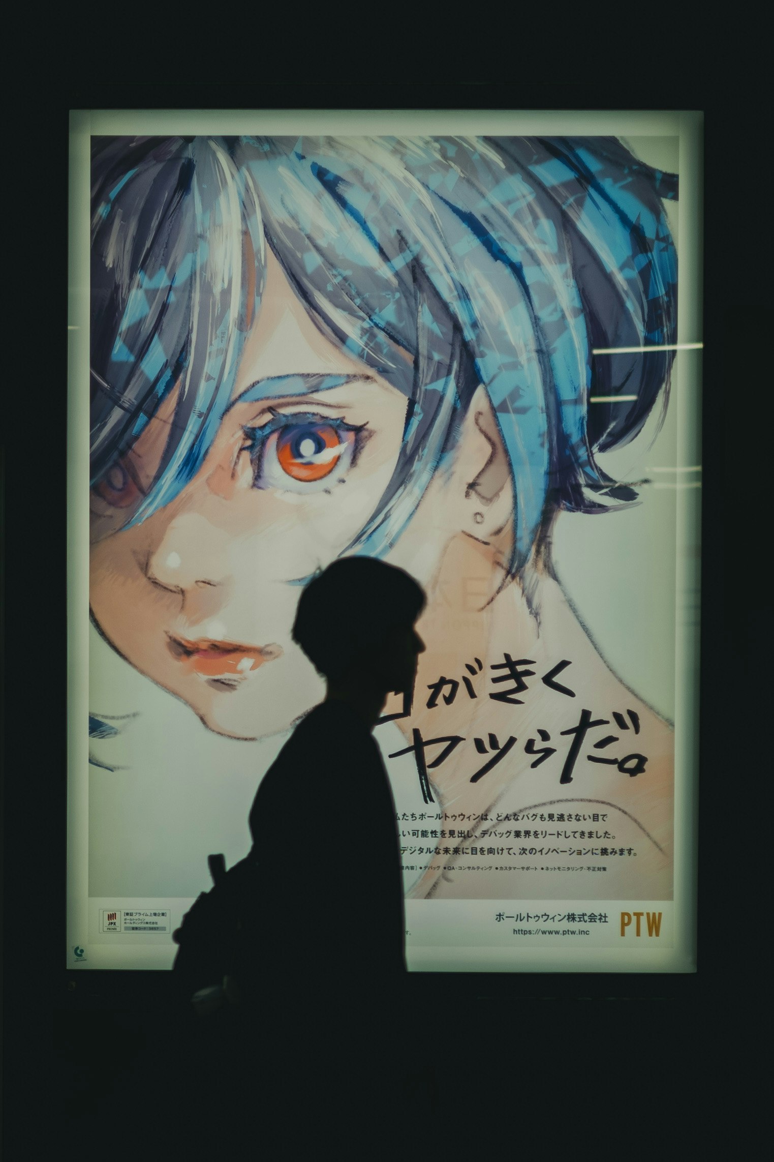 Silhouette of a person passing by a poster featuring a woman with blue hair