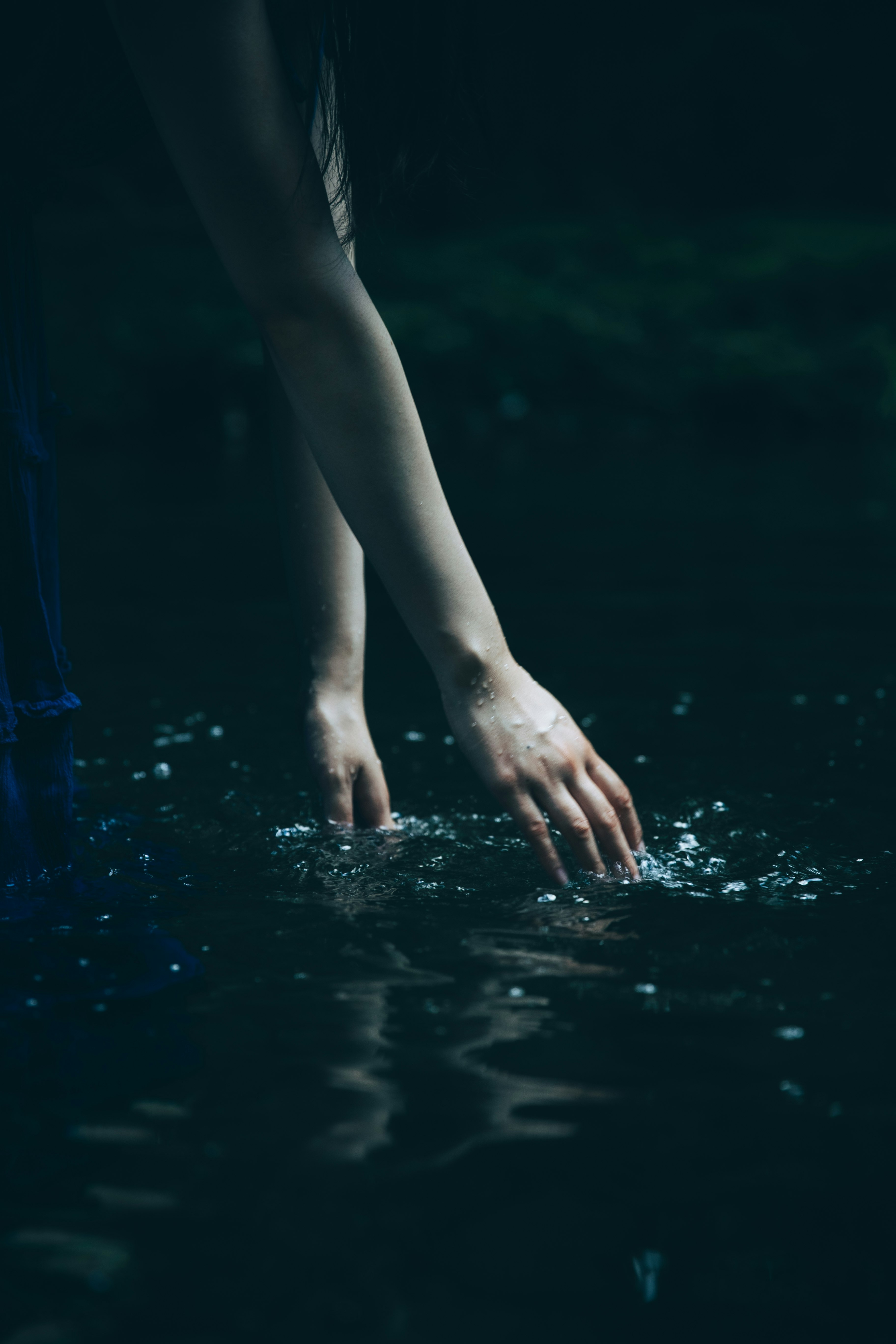 暗い水面に手を入れる人物の手元