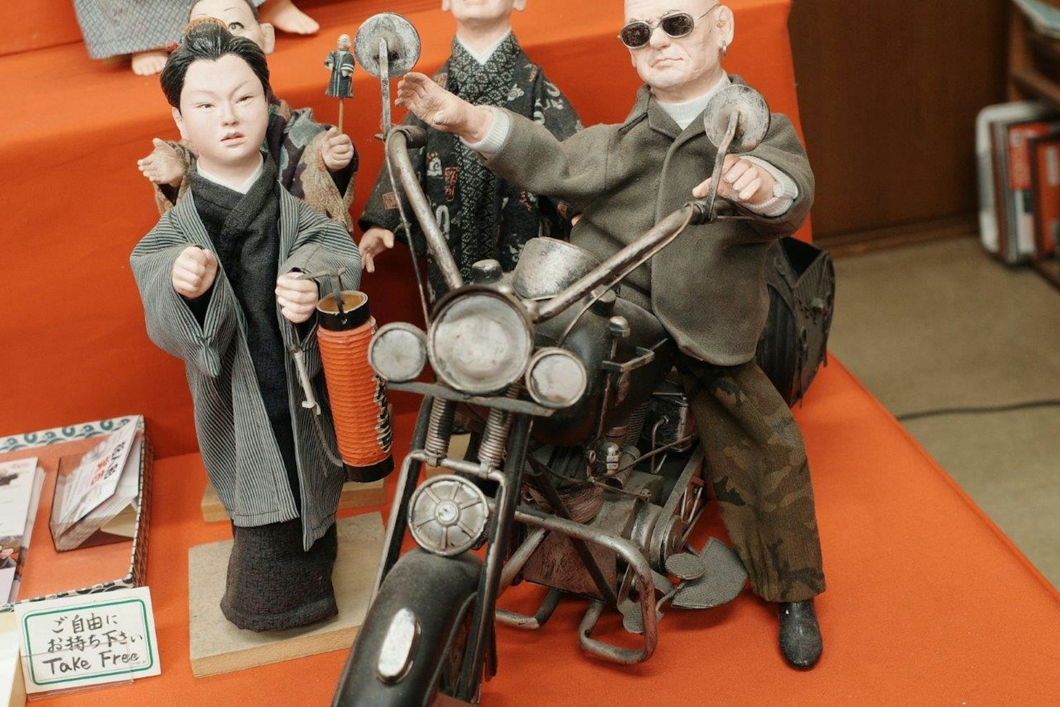 Figuras en una motocicleta con un fondo naranja