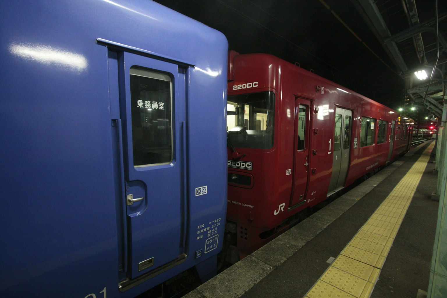 Blue train and red train parked at night station