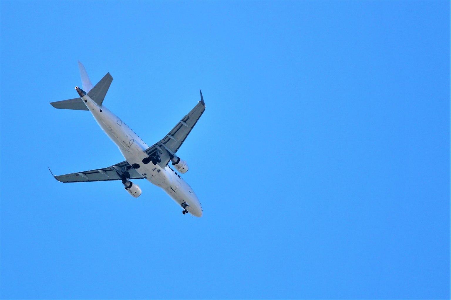 Avion de passagers volant dans un ciel bleu clair vu d'en dessous