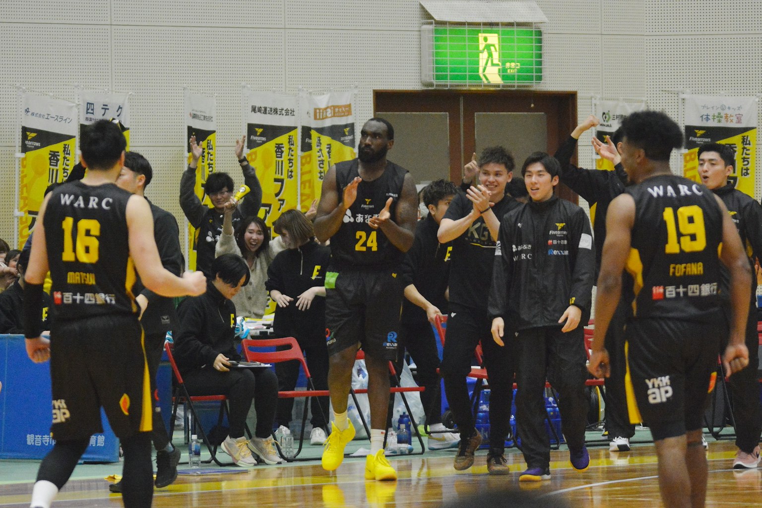 Giocatori di basket in azione durante una partita con compagni che fanno il tifo