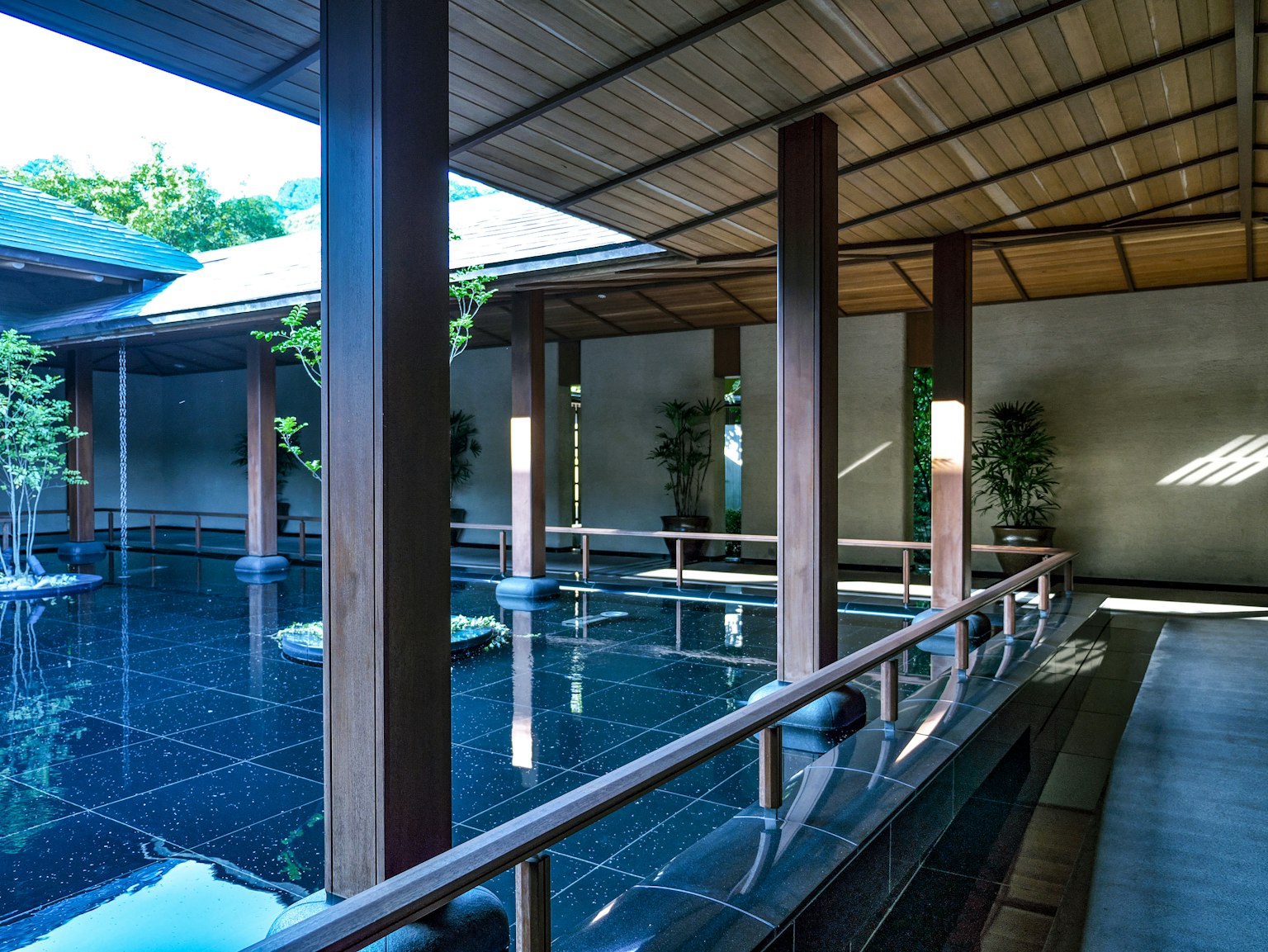 Nội thất của onsen Nhật Bản hiện đại với ao đá đen và cột gỗ