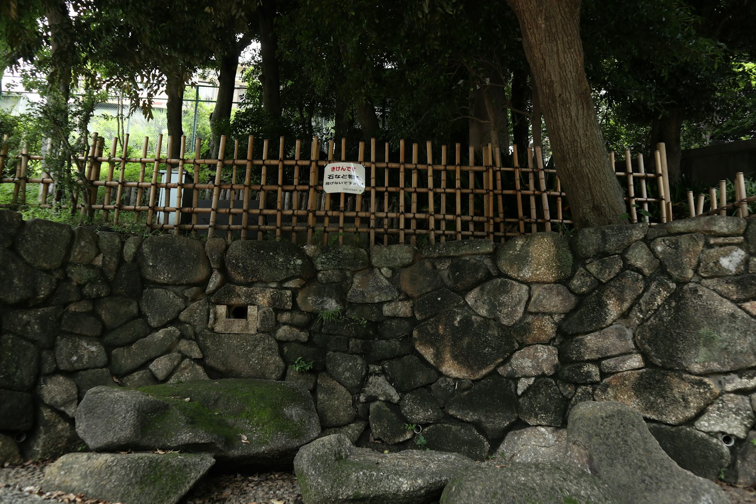 Muro de piedra con cerca de bambú en un entorno verde