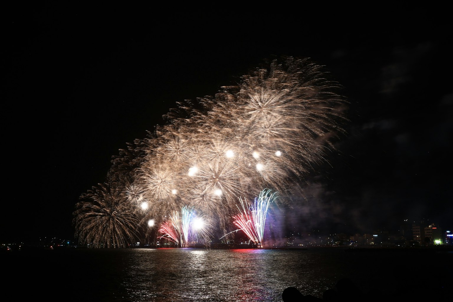 Spettacolo di fuochi d'artificio nel cielo notturno luci colorate che si riflettono sull'acqua