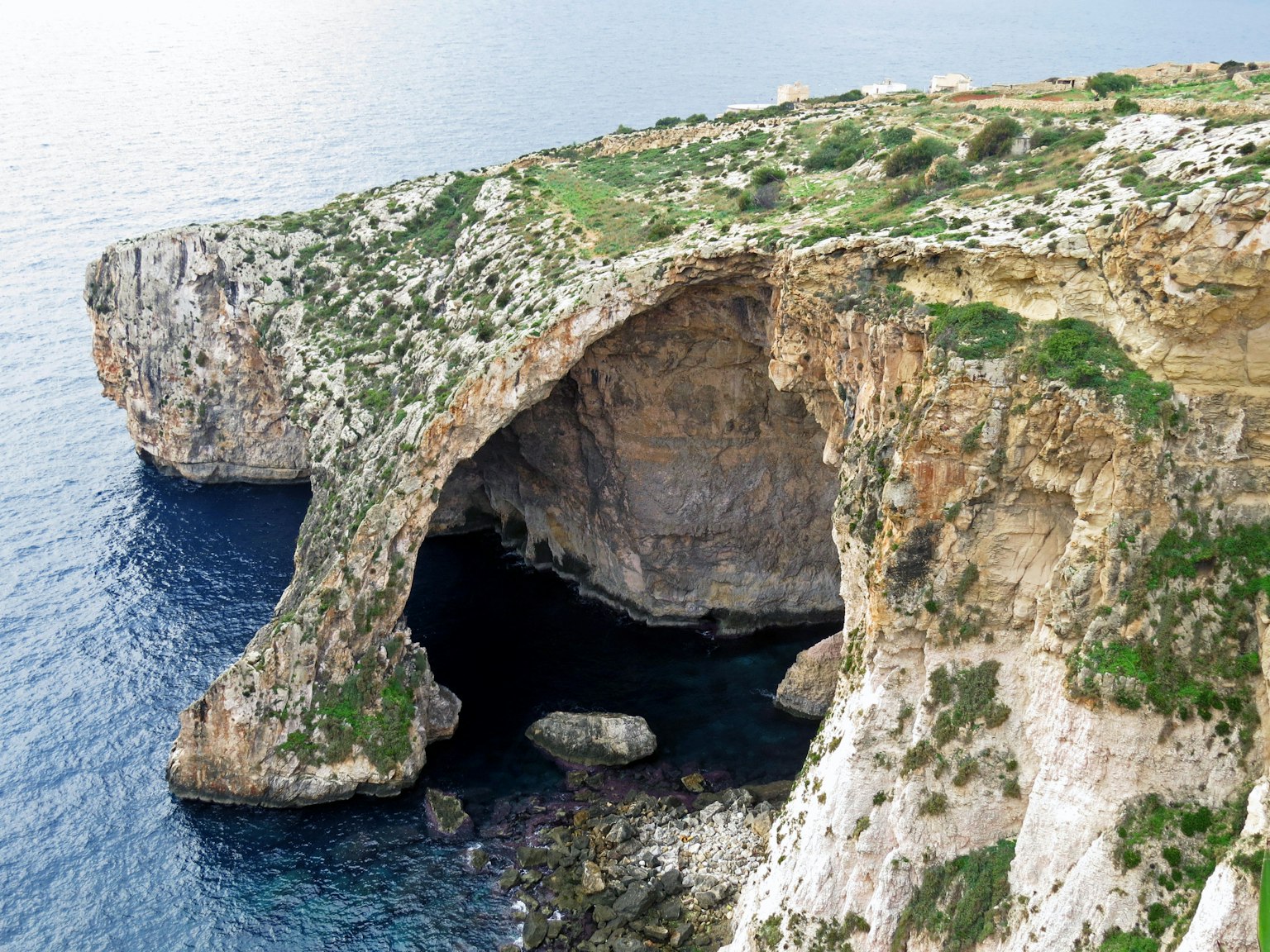 Scenic view of a rocky cliff with lush greenery overlooking the sea