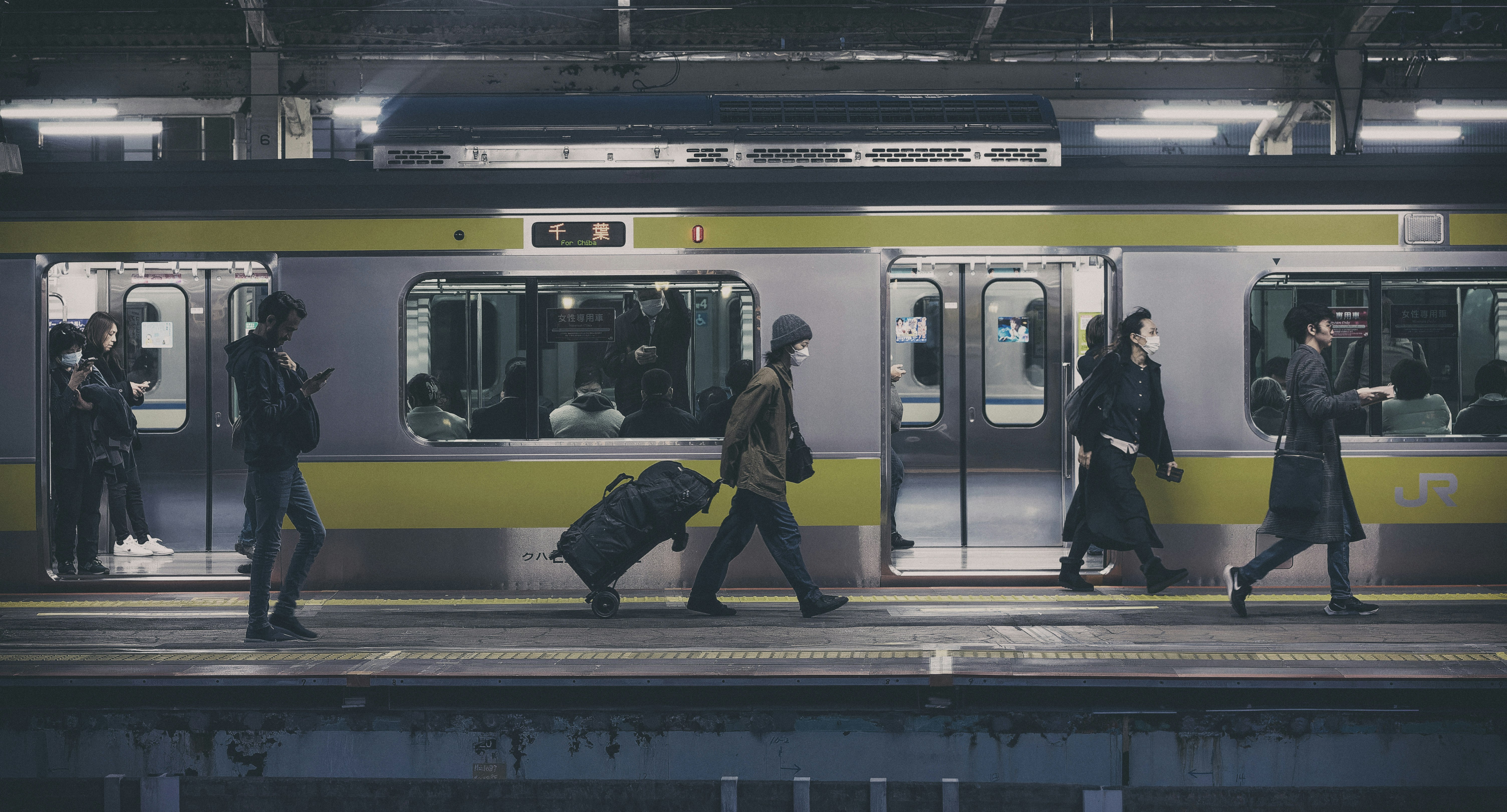 Street scene with people walking along a train platform and passing train cars