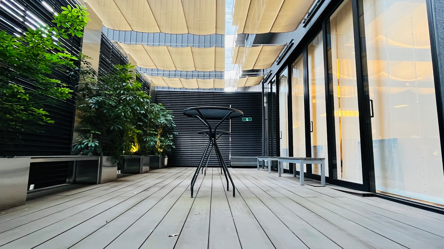 Balcone moderno con un tavolo nero e vegetazione
