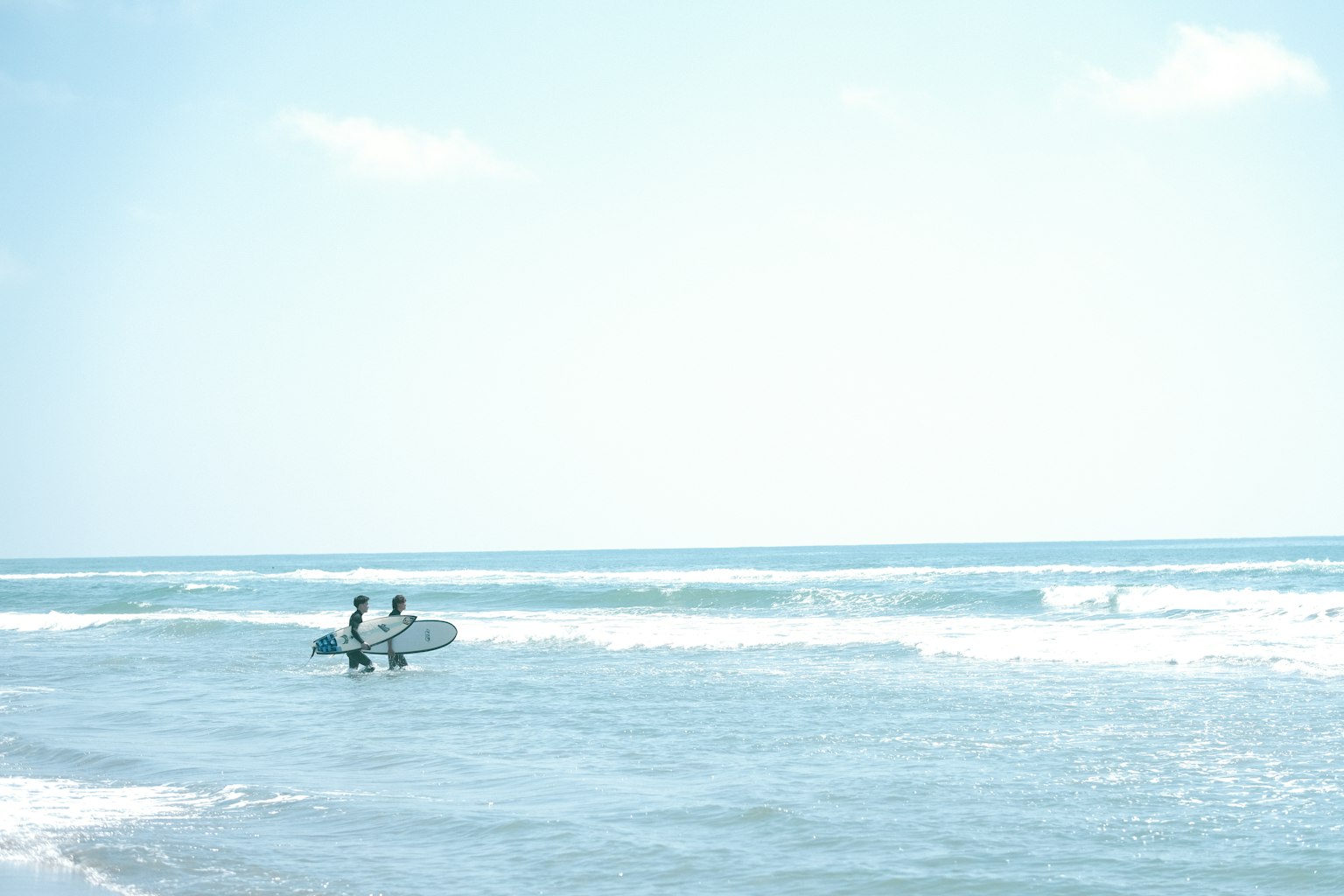 两名冲浪者在蓝天和波浪中享受海洋