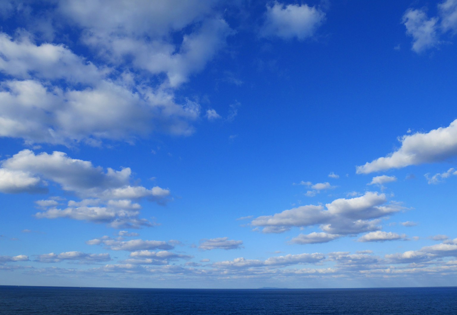 Vast blue sky with white clouds over the ocean