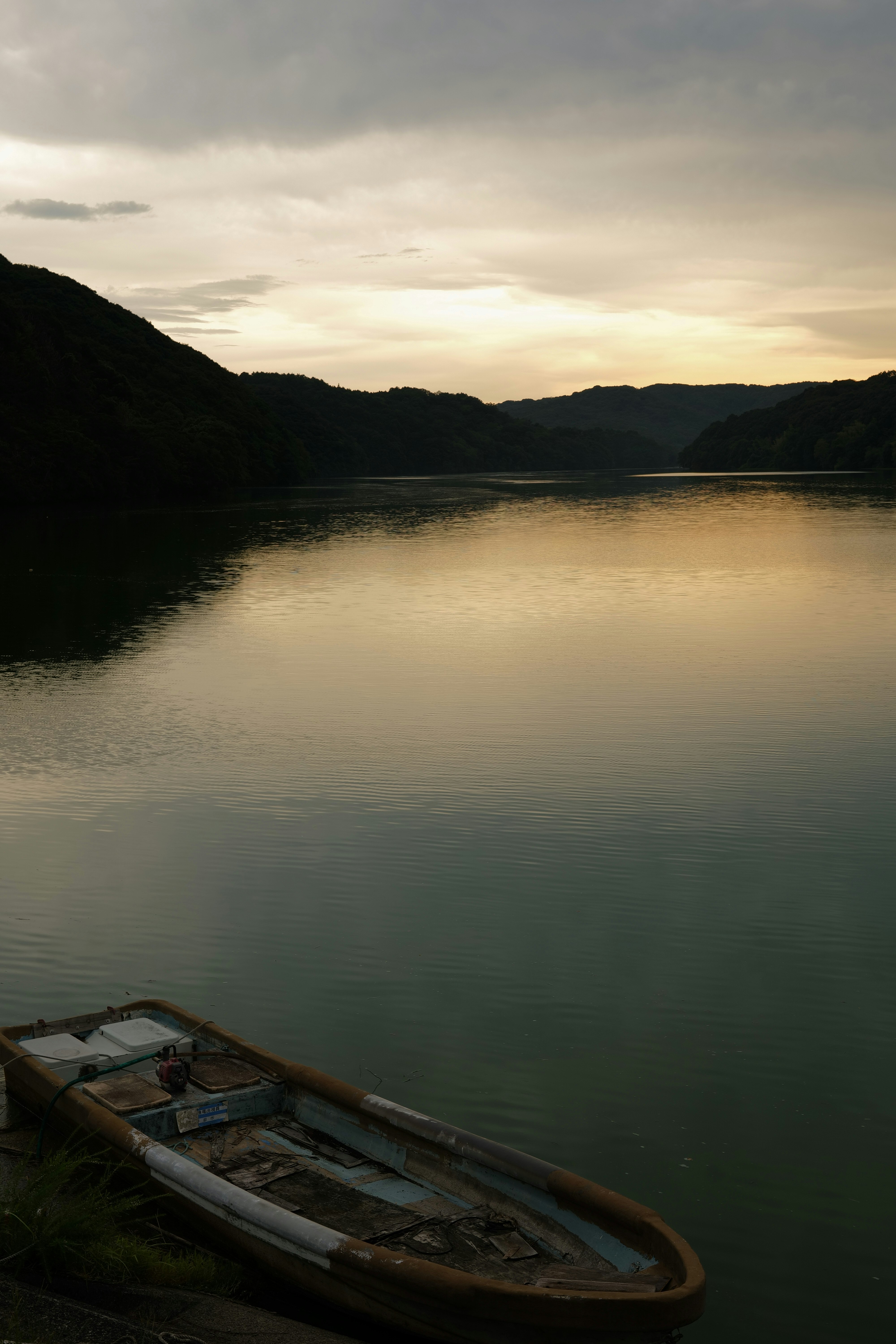 日没の静かな湖面と小舟のある岸辺