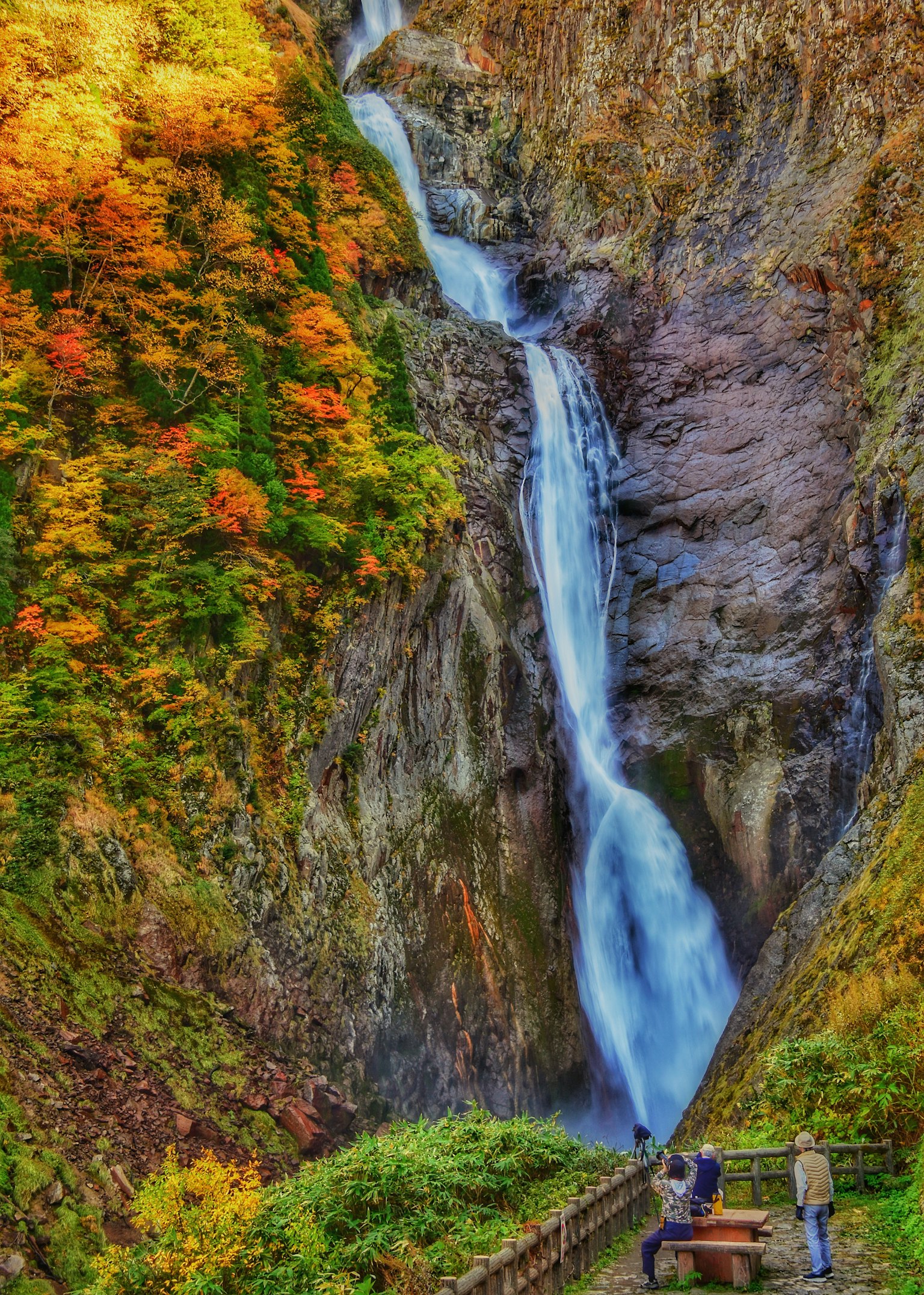 Schöner Wasserfall umgeben von Herbstlaub mit Touristen