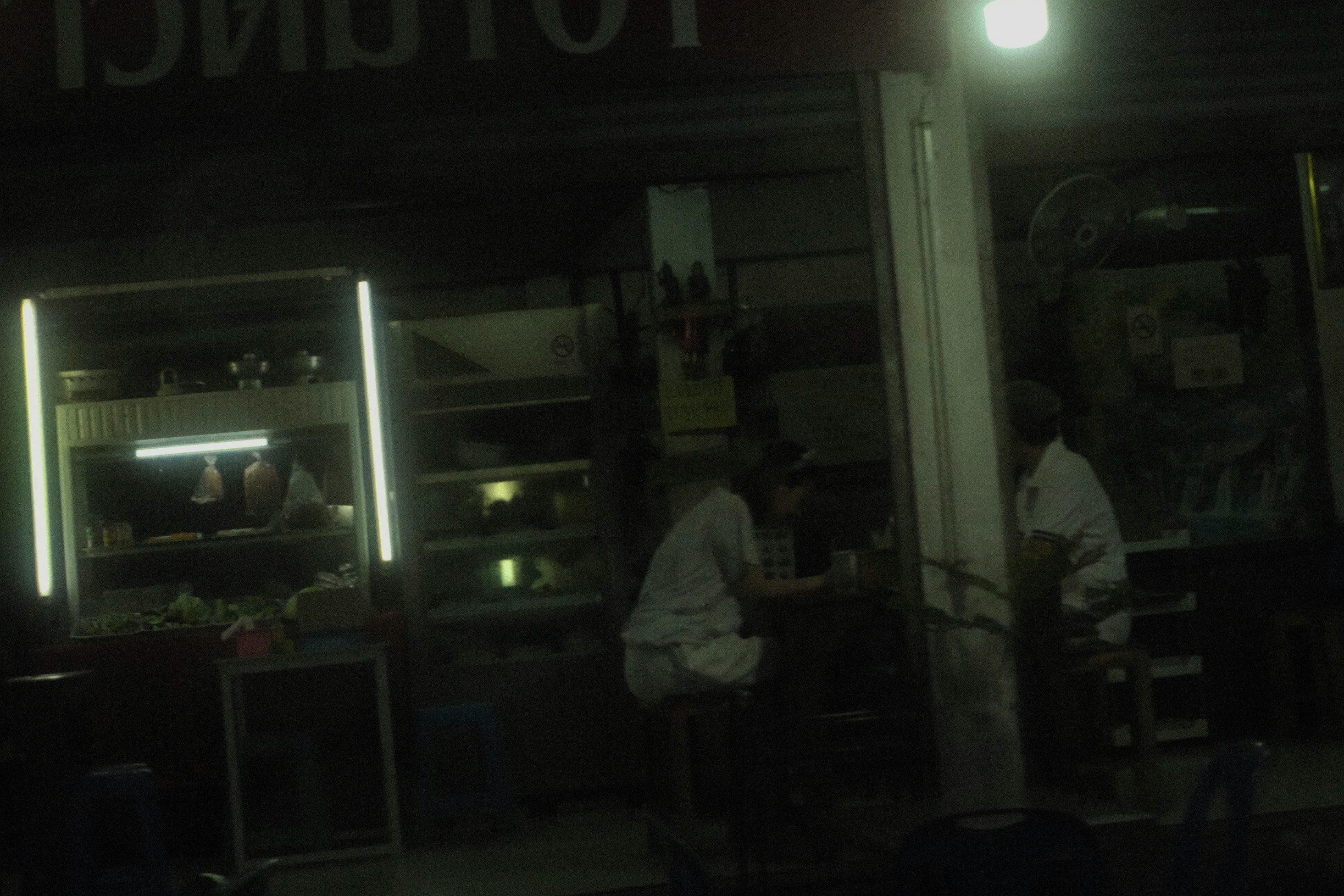 夜の屋台風の店先で作業する人々のいる路地