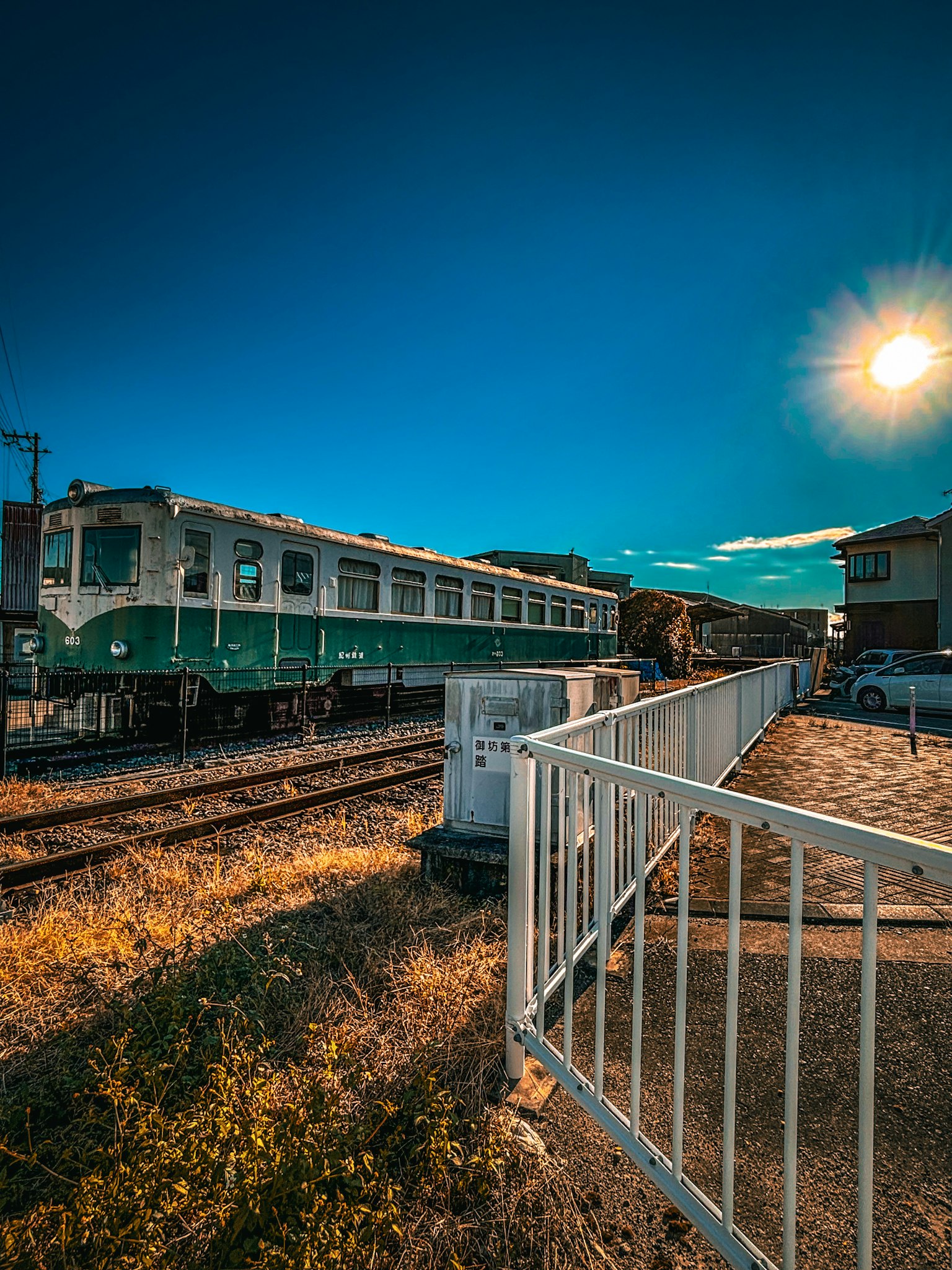 Treno verde e bianco fermo sotto un cielo blu con paesaggio circostante