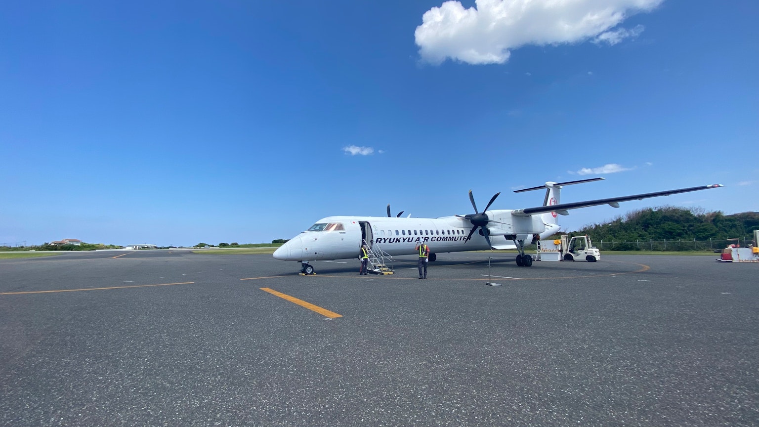 Aereo turbopropulsore bianco parcheggiato sulla pista sotto un cielo blu