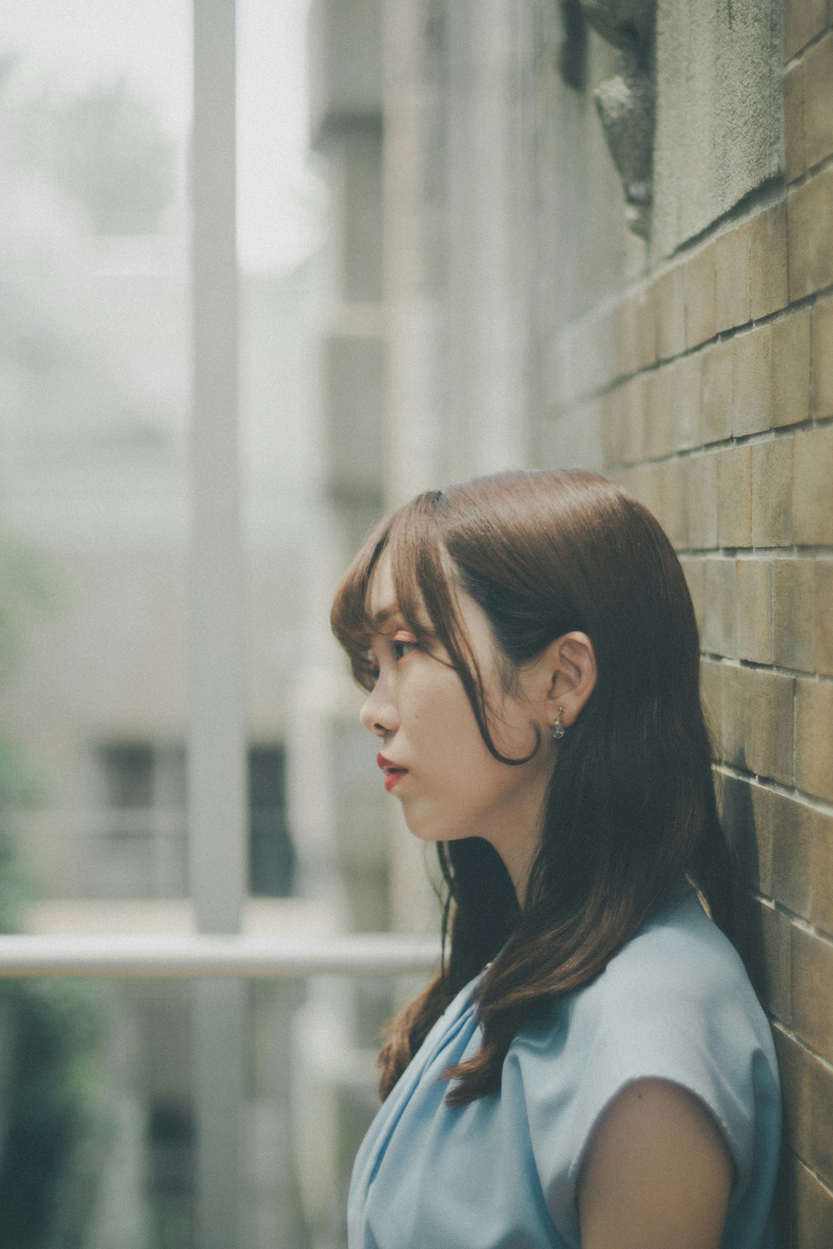 壁沿いに立つ横顔の女性