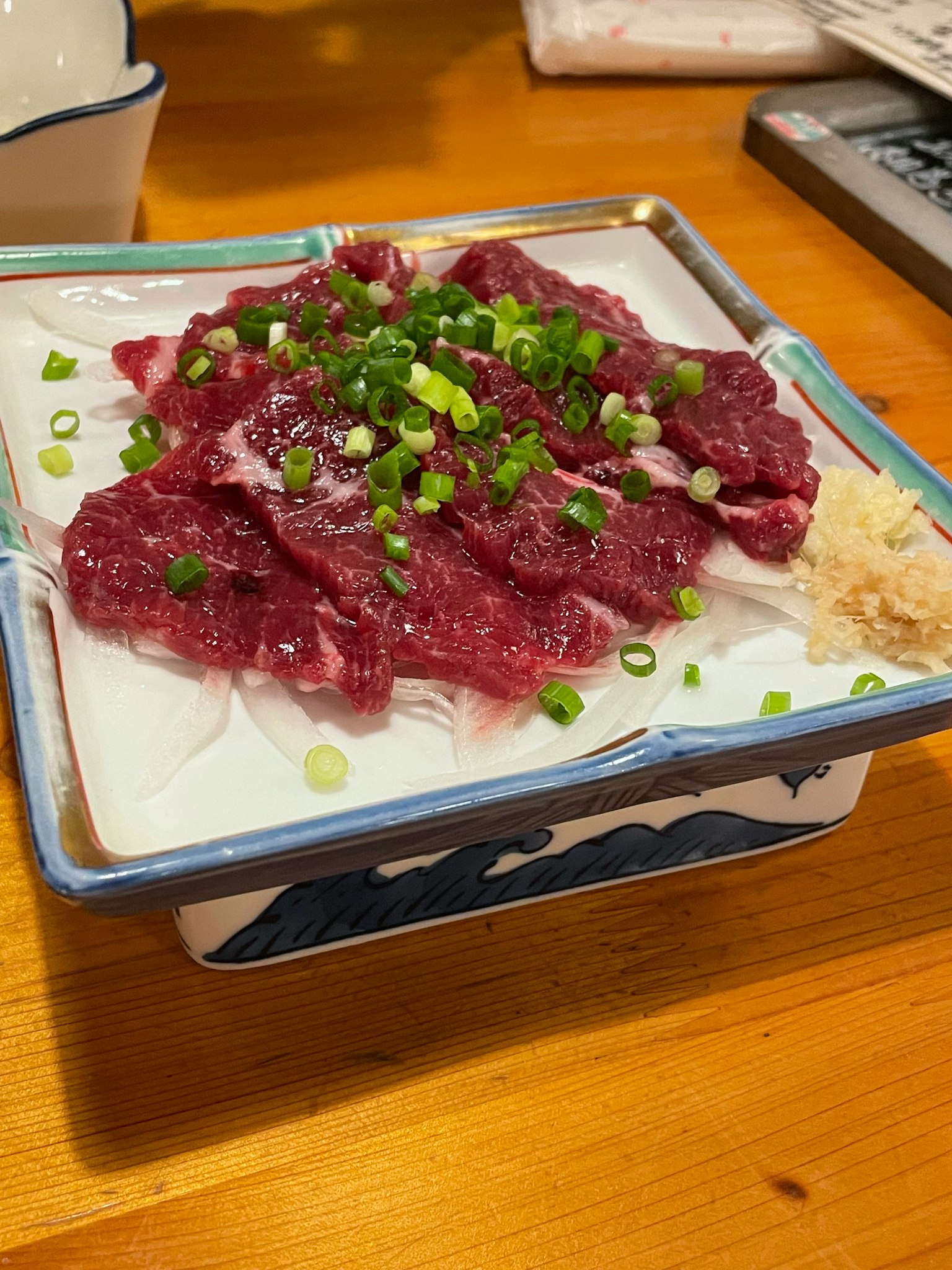牛肉刺身盤上放有青蔥和生薑
