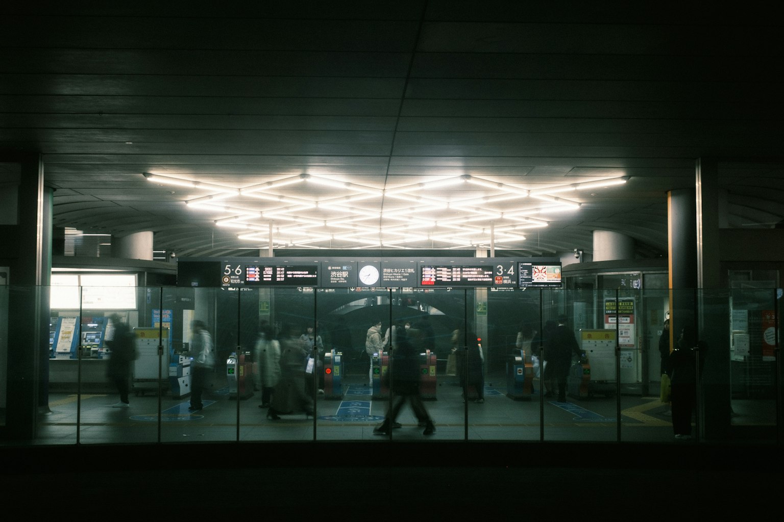 Persone che si radunano all'ingresso di una stazione con illuminazione brillante