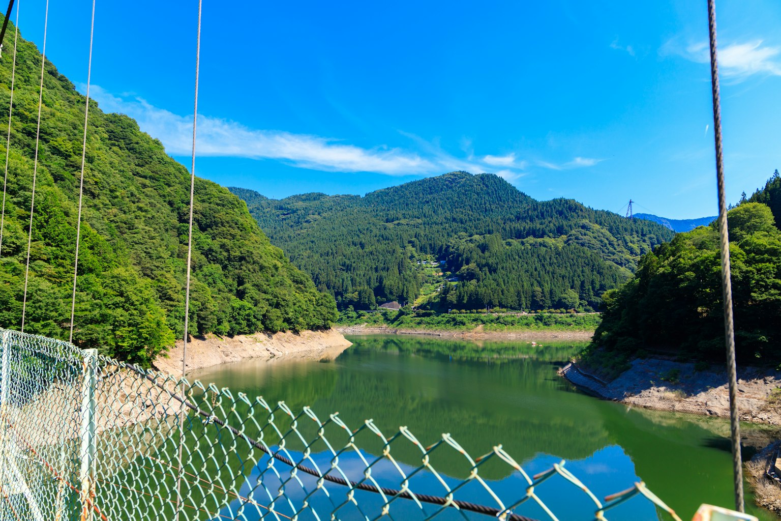 Malersicher Blick auf Berge und See unter blauem Himmel mit Brückenkabeln