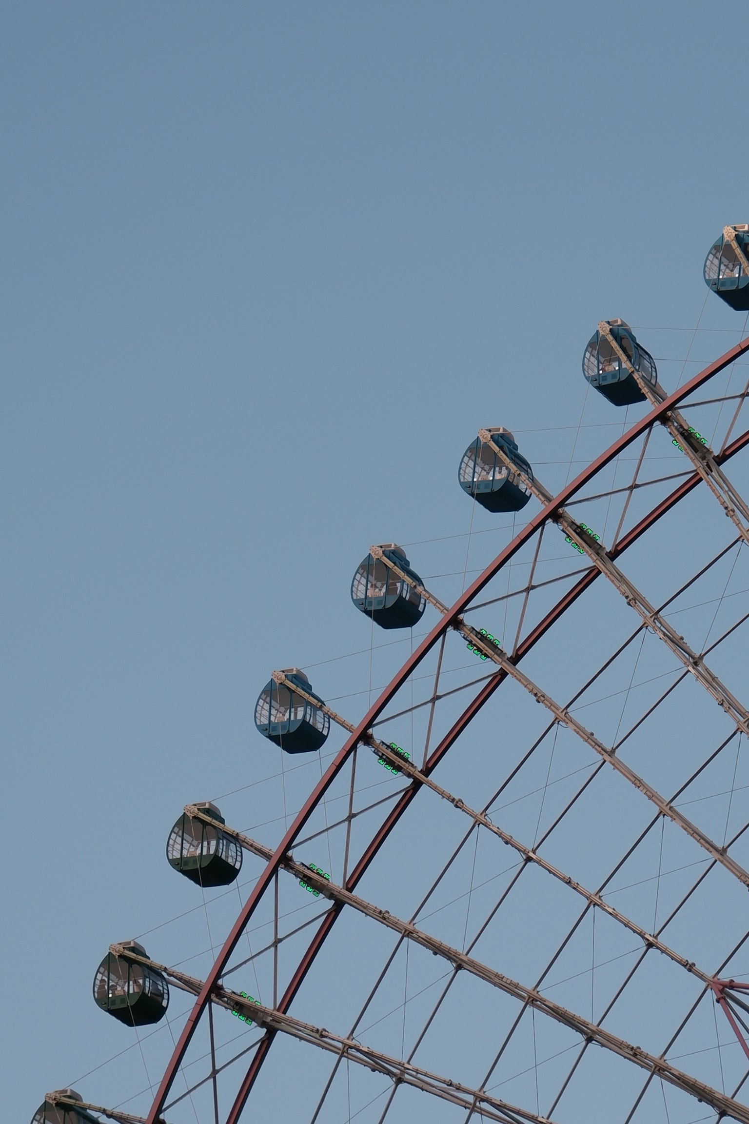 Bagian atas roda ferris dengan kapsul di bawah langit biru