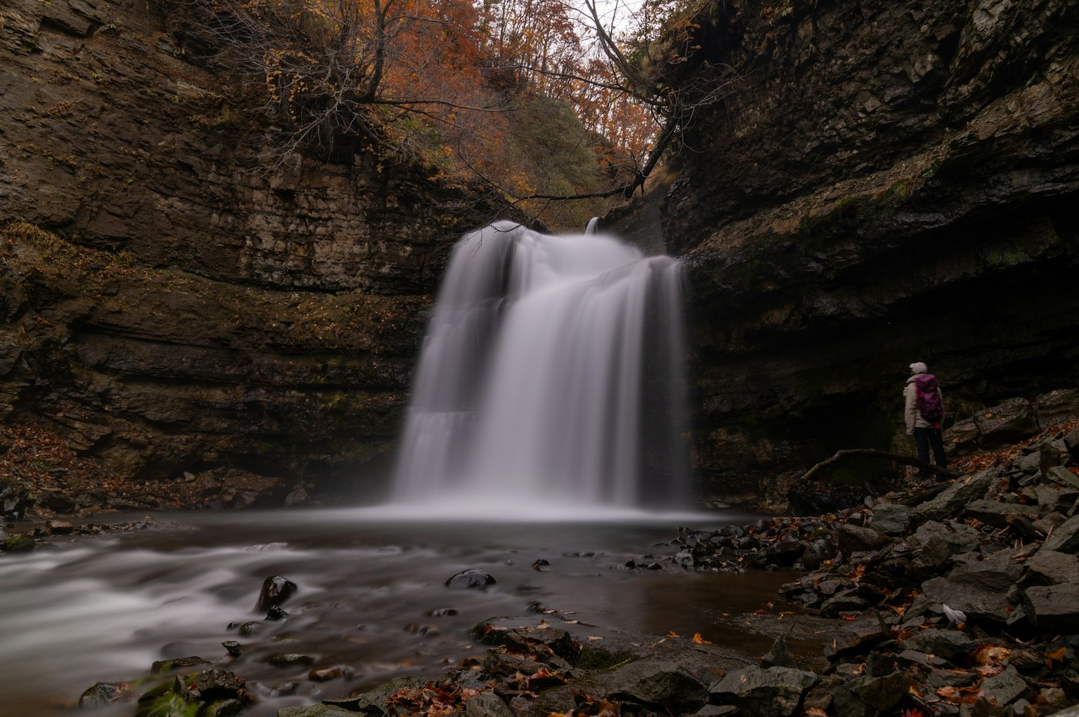 Wanderer steht neben einem schönen Wasserfall in einer felsigen Schlucht