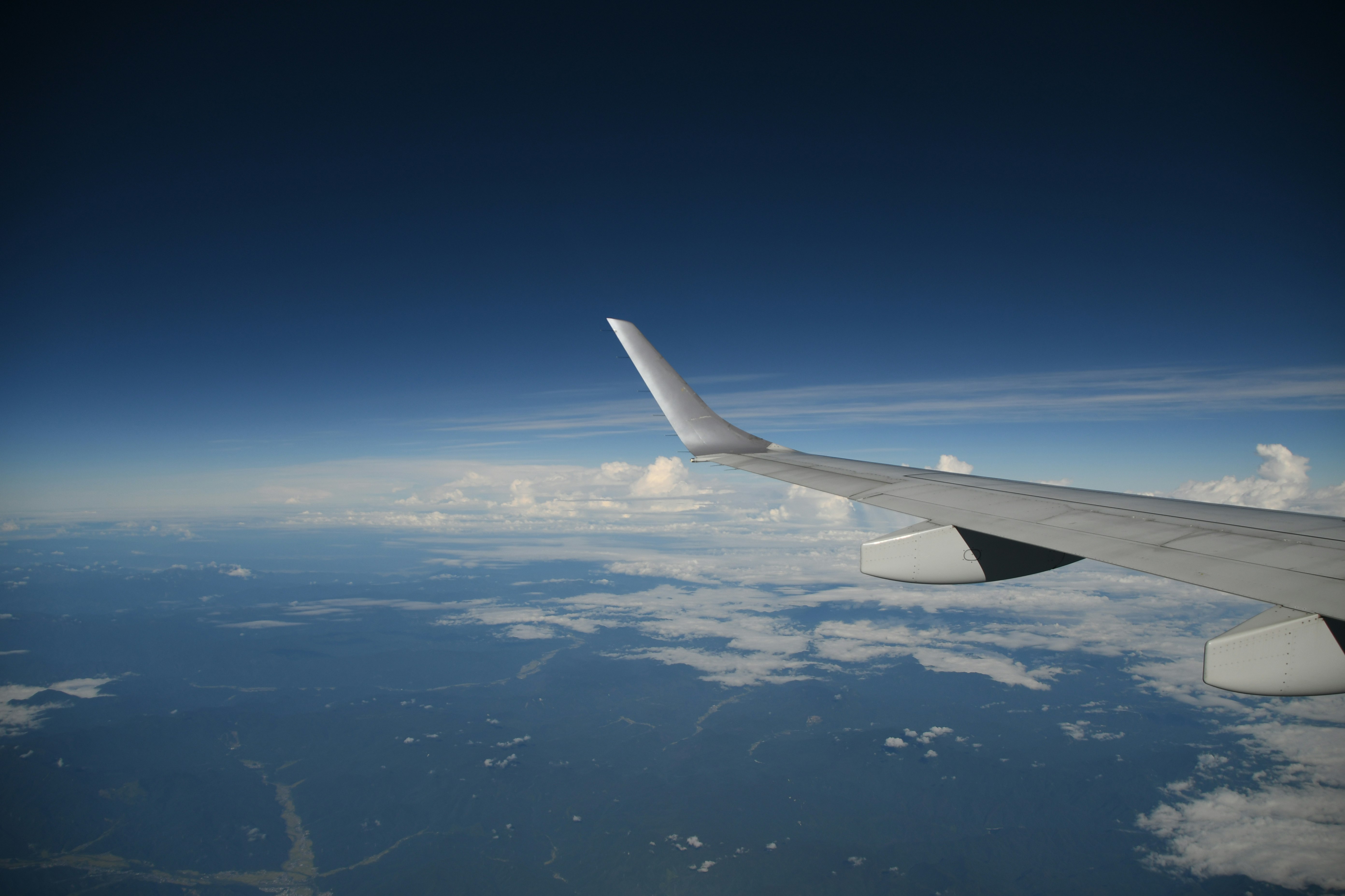 飛行機の窓から見える雲と大地の上空