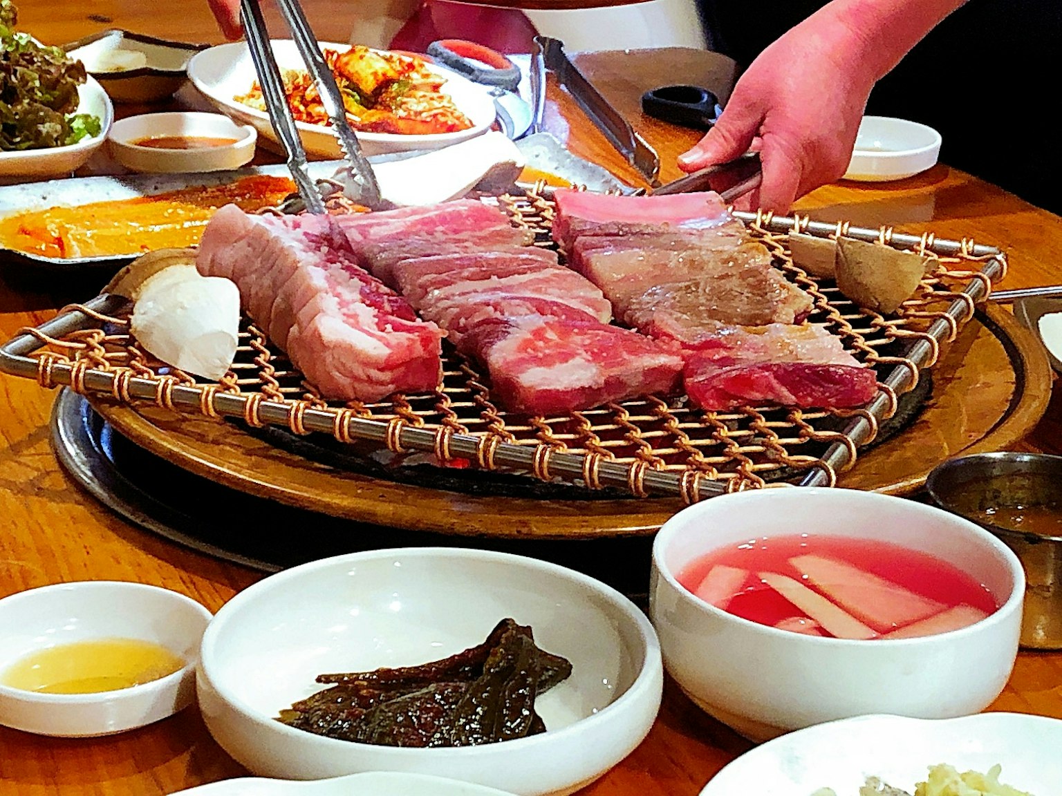 Tavolo di barbecue coreano con carne grigliata e vari contorni