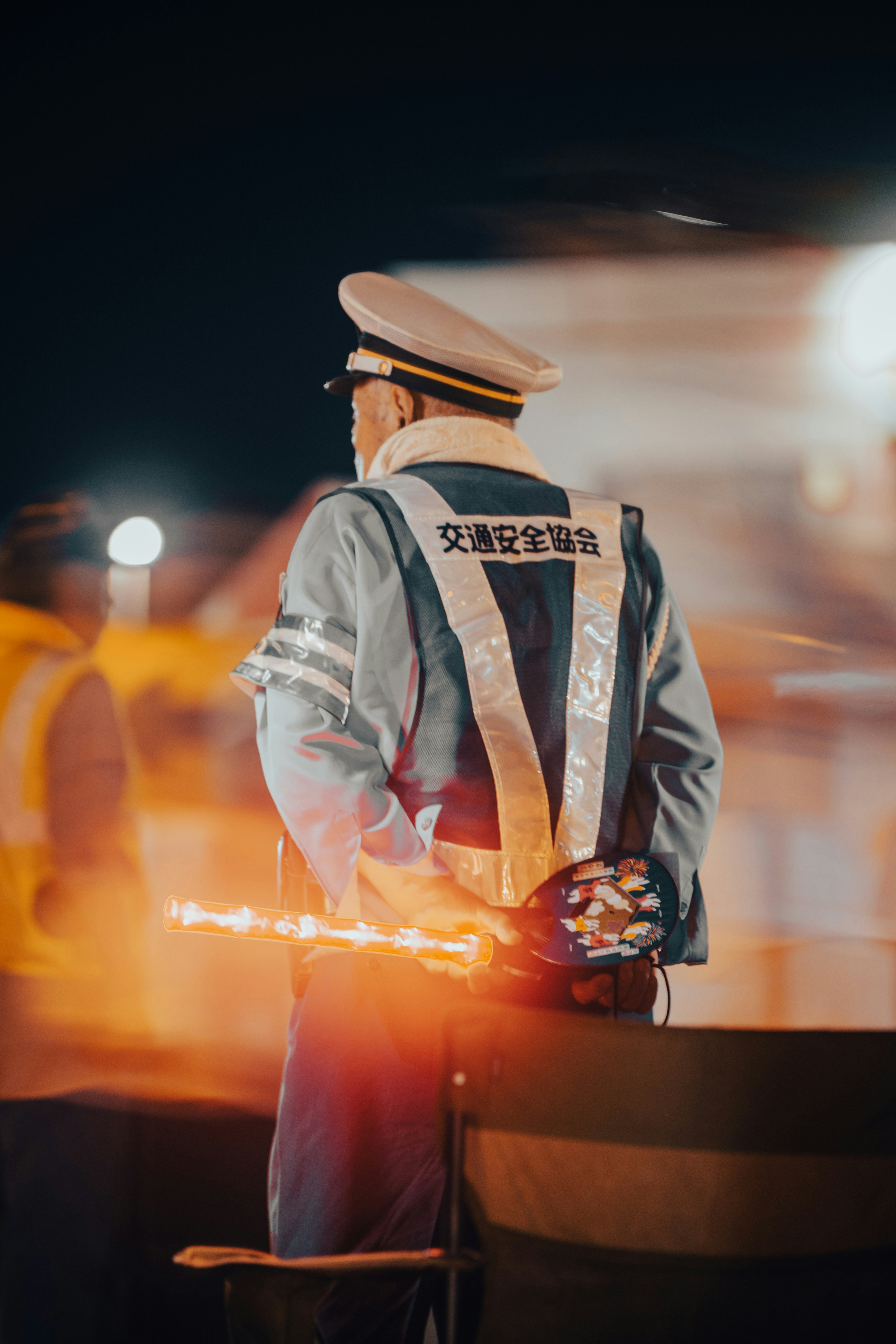 夜の道路で交通整理をする制服の警備員