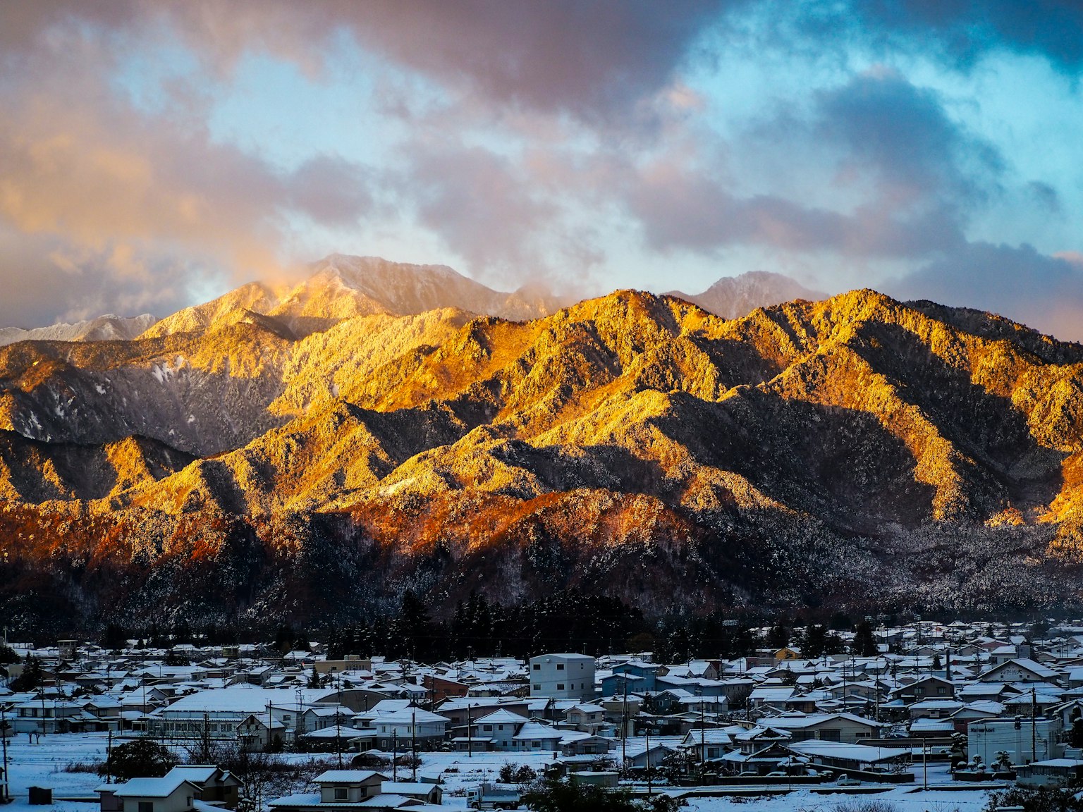 Ciudad nevada con montañas al atardecer