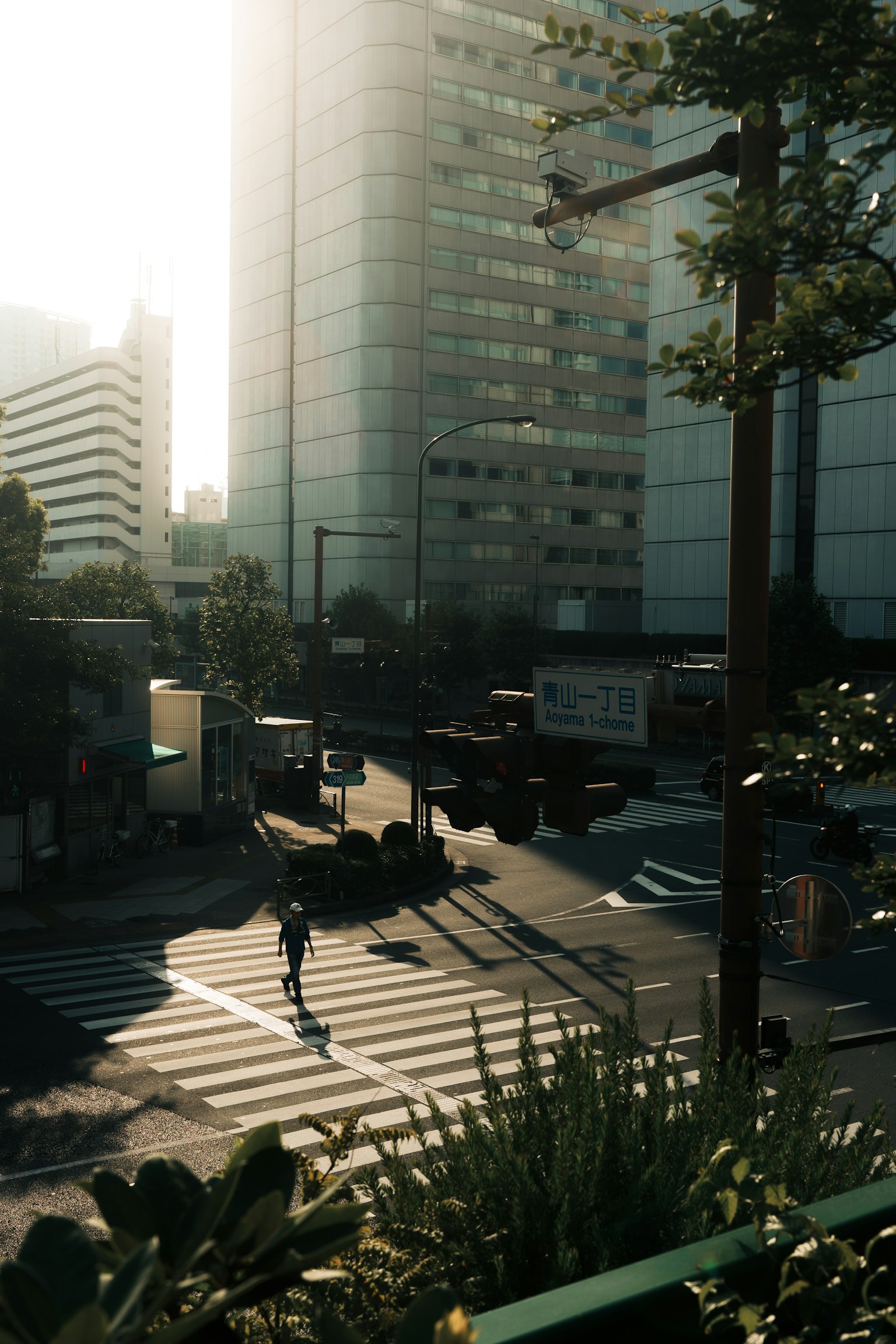 Urban intersection with tall buildings and sunlight casting shadows