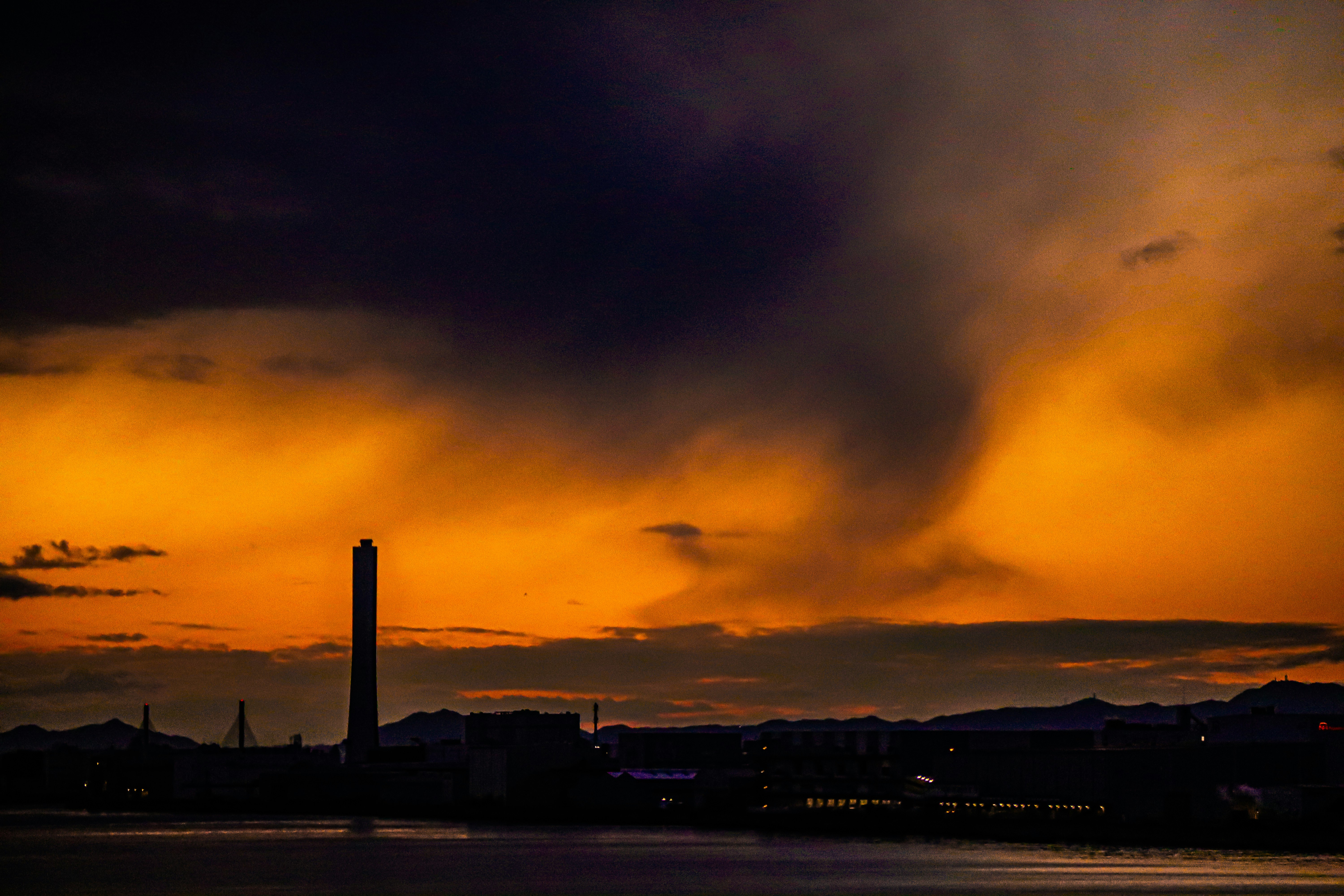 夕焼けの空に雨雲が広がる海辺の景色