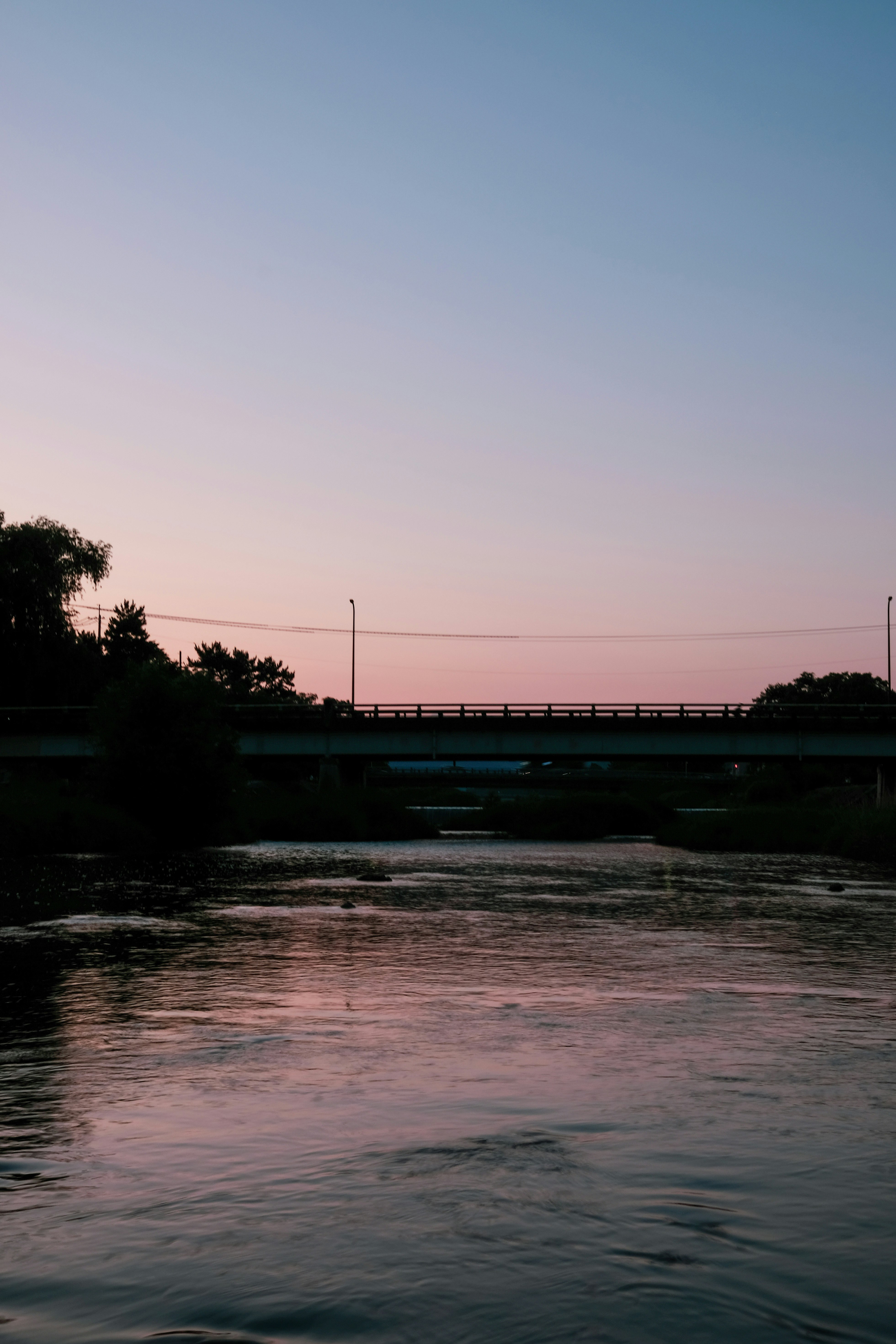 cielo de atardecer sobre un río con un puente en silueta