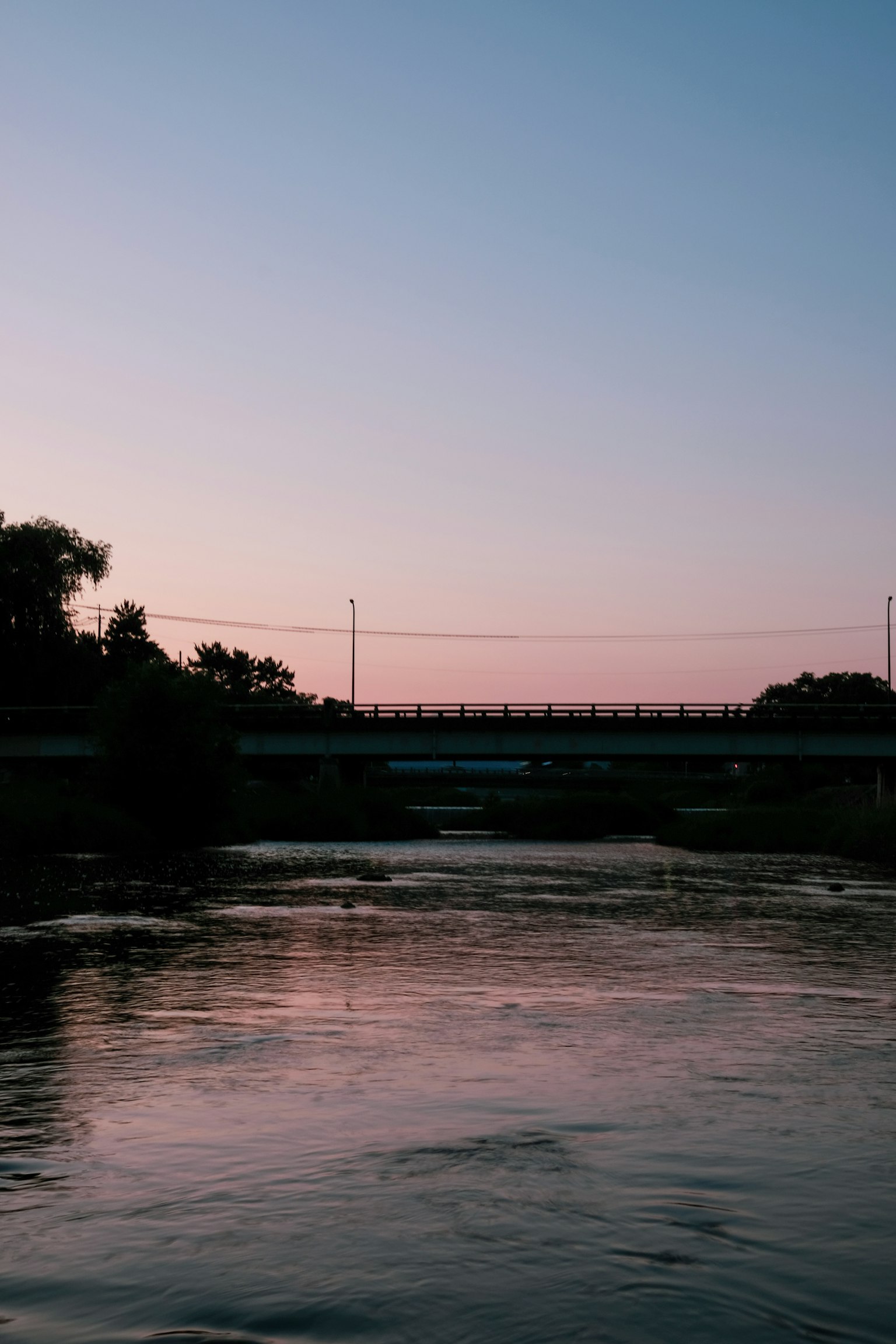 Vista escénica de un río al atardecer con un puente al fondo
