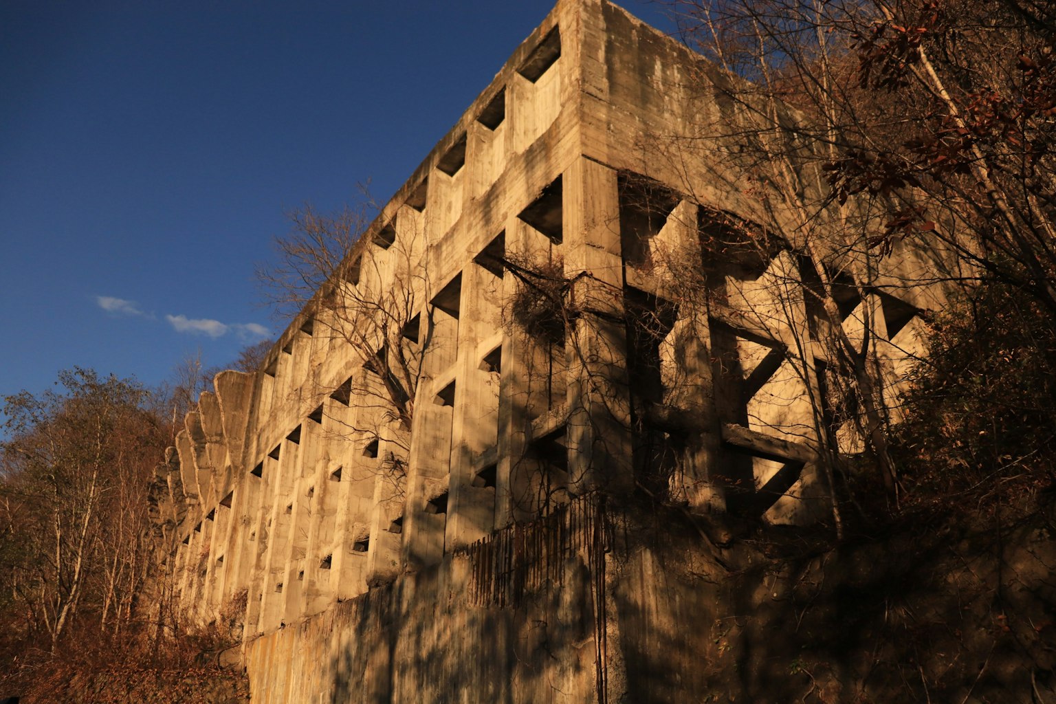 Un côté d'un bâtiment en béton usé illuminé par la lumière du coucher de soleil