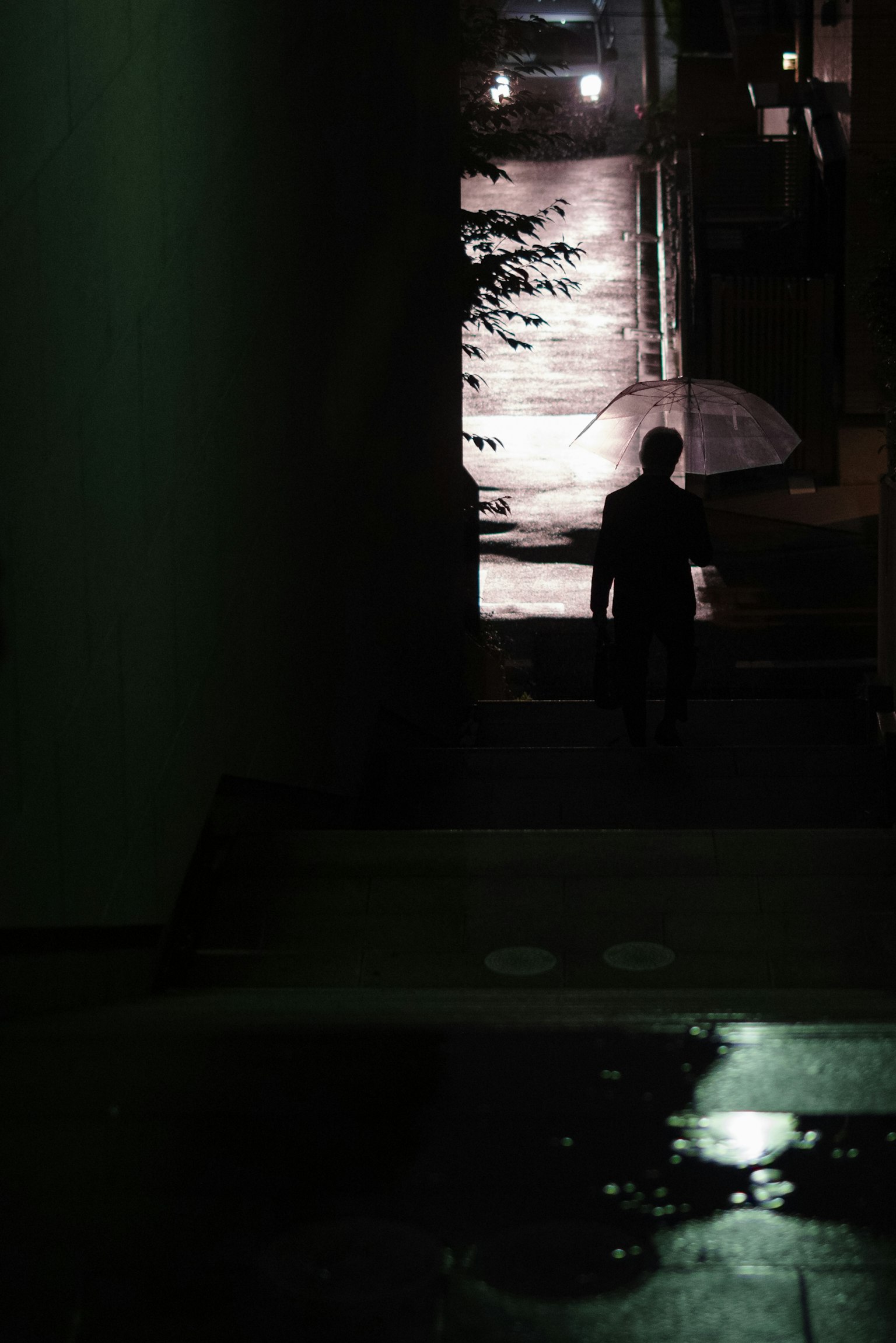 Silhouette of a person walking through a dark corridor with reflections on the water