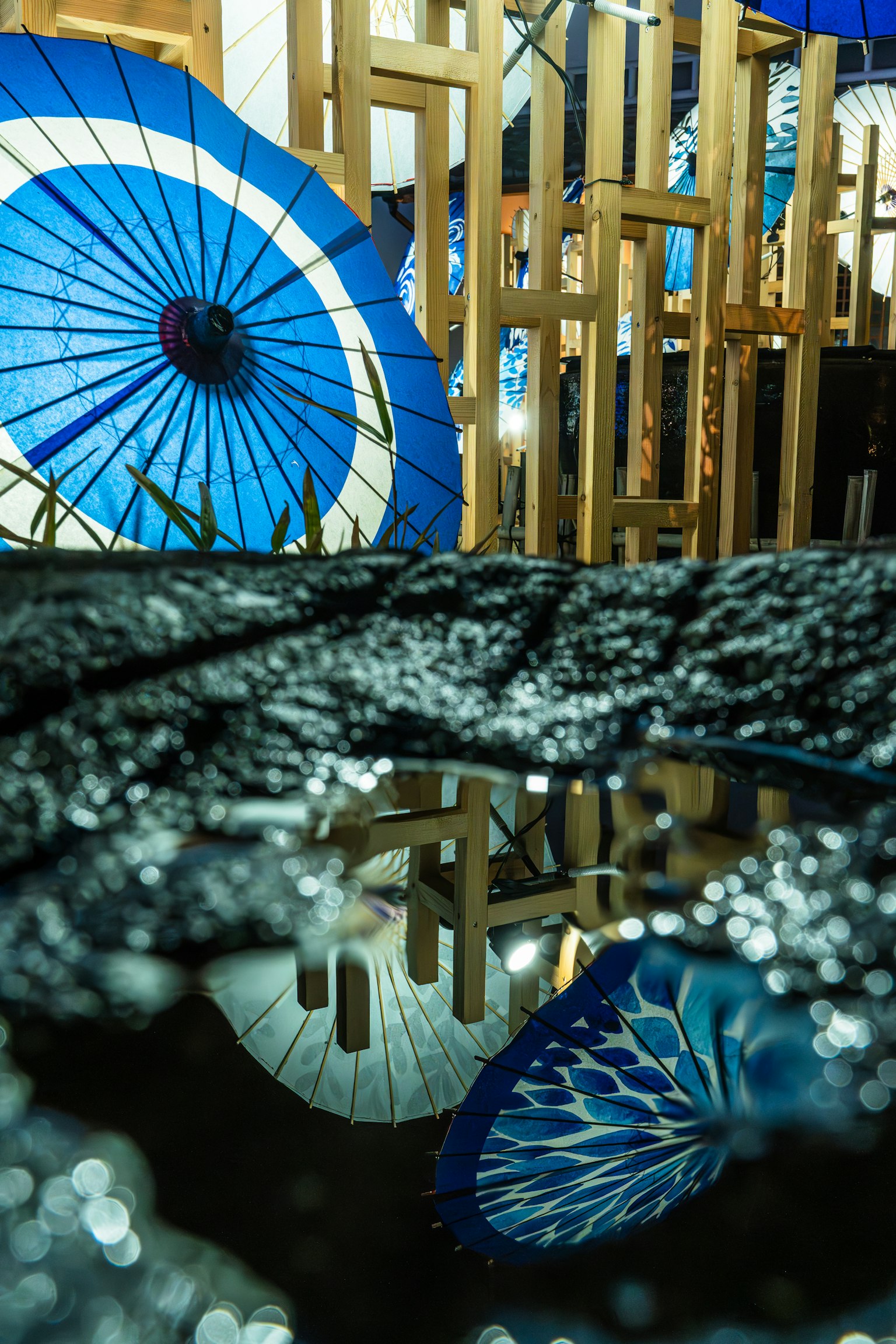Blue umbrellas reflected in water with a wooden background