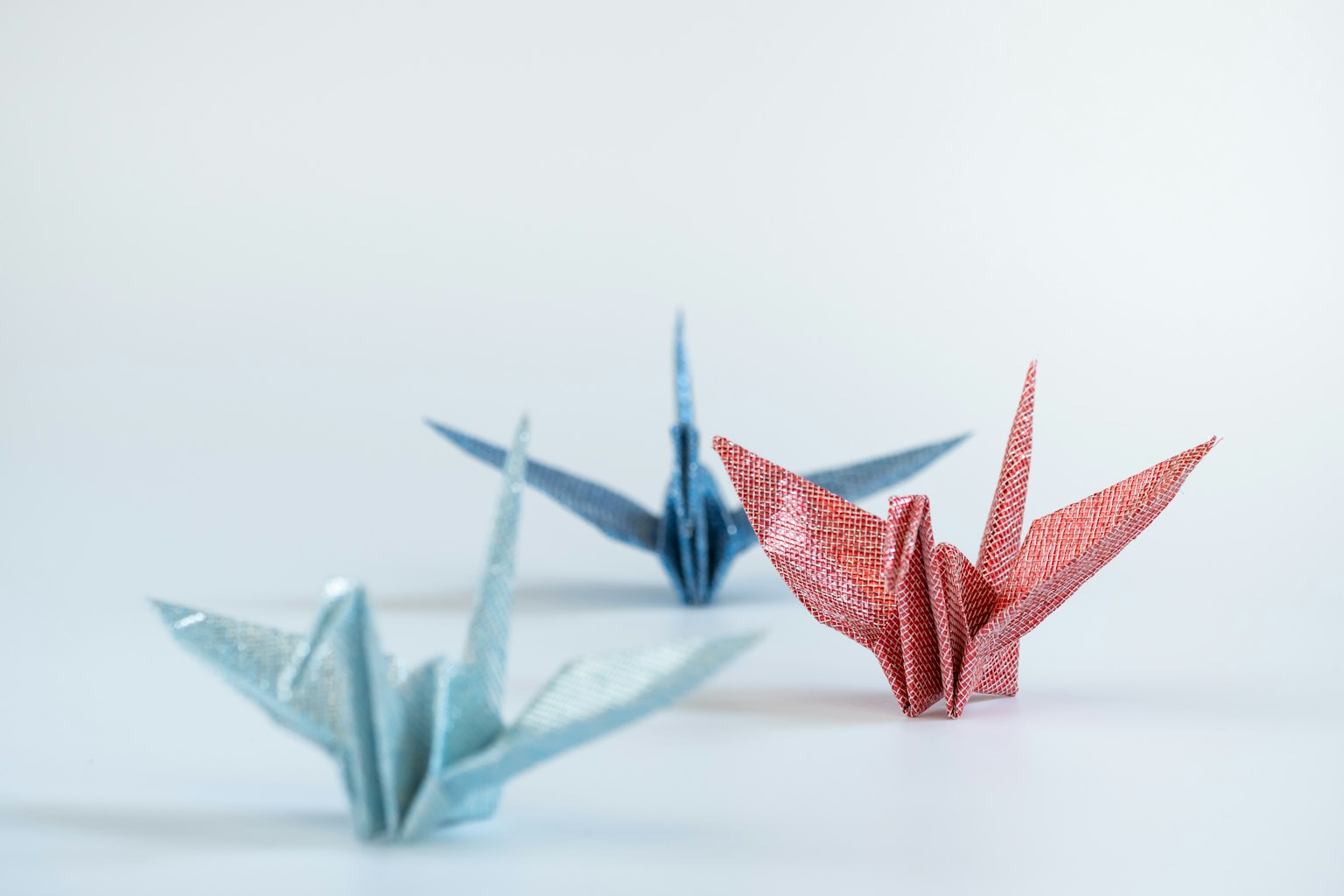 Blaue und rote Origami-Kraniche vor einem schlichten Hintergrund