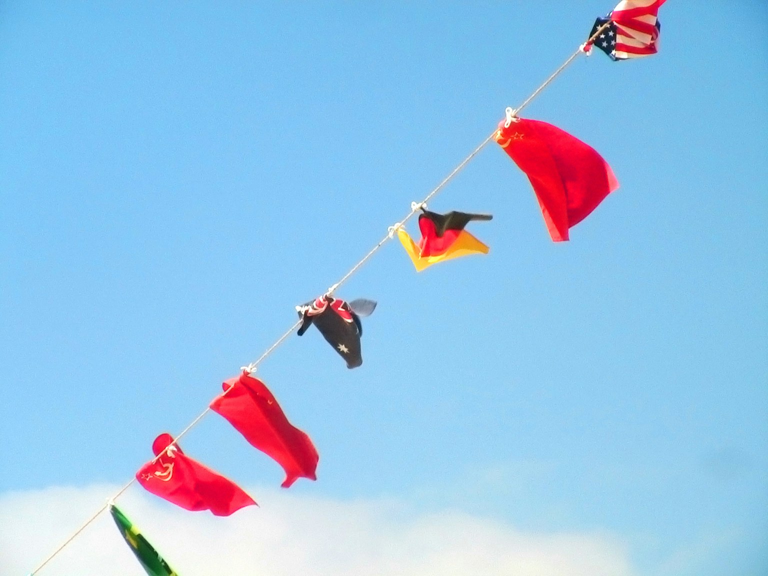 Colorful international flags hanging against a blue sky