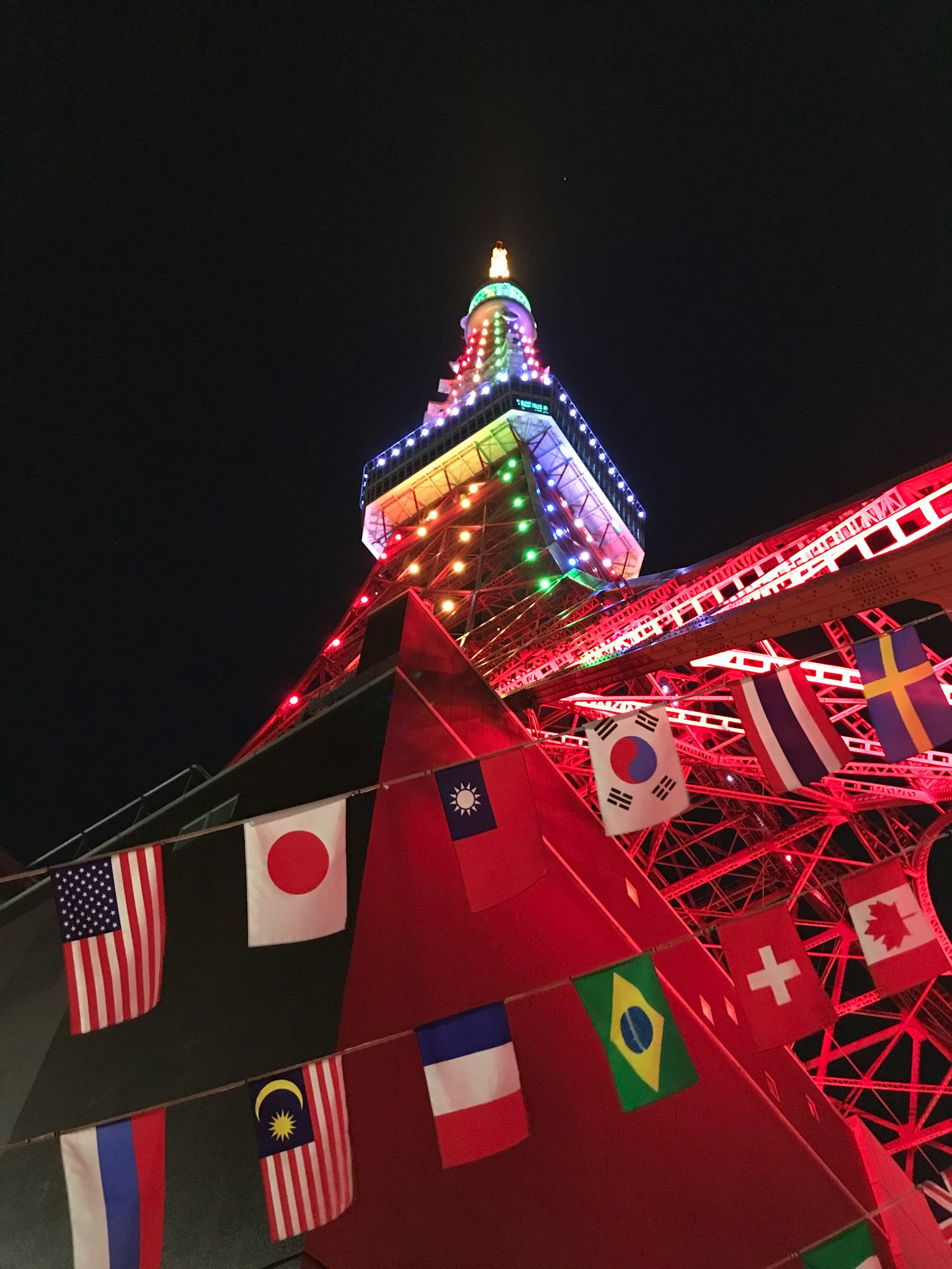 Tour de Tokyo illuminée la nuit avec divers drapeaux nationaux